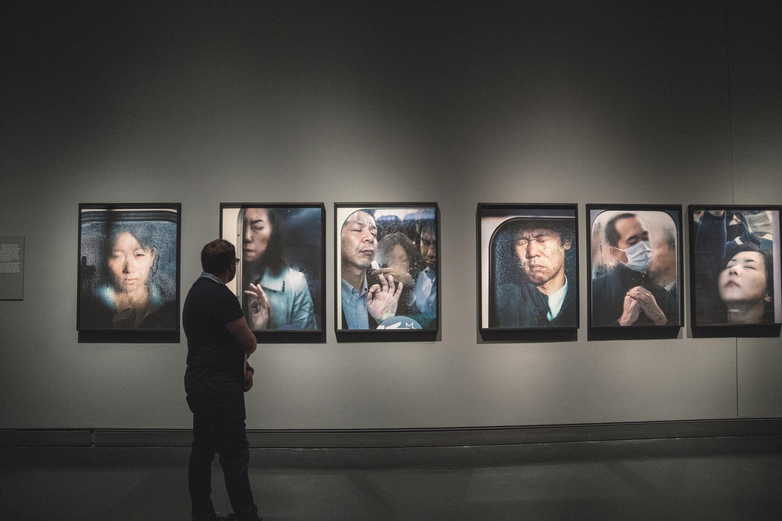 man looking at realism images in art gallery