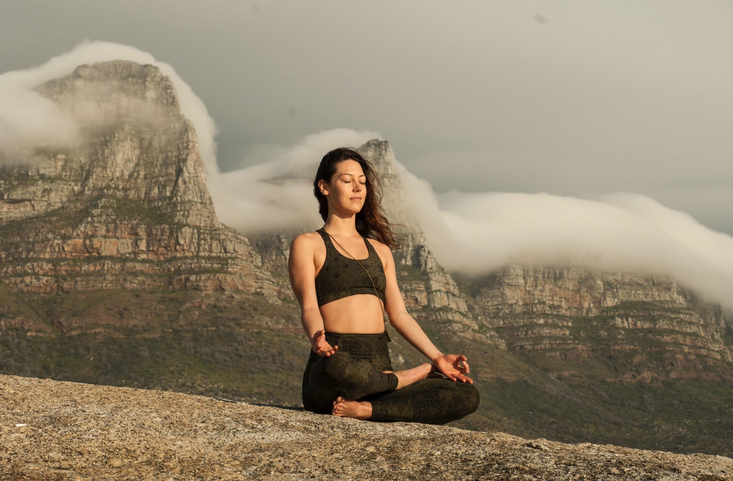 woman engaged in meditation in front of twelve apostles mountain range, Cape Town