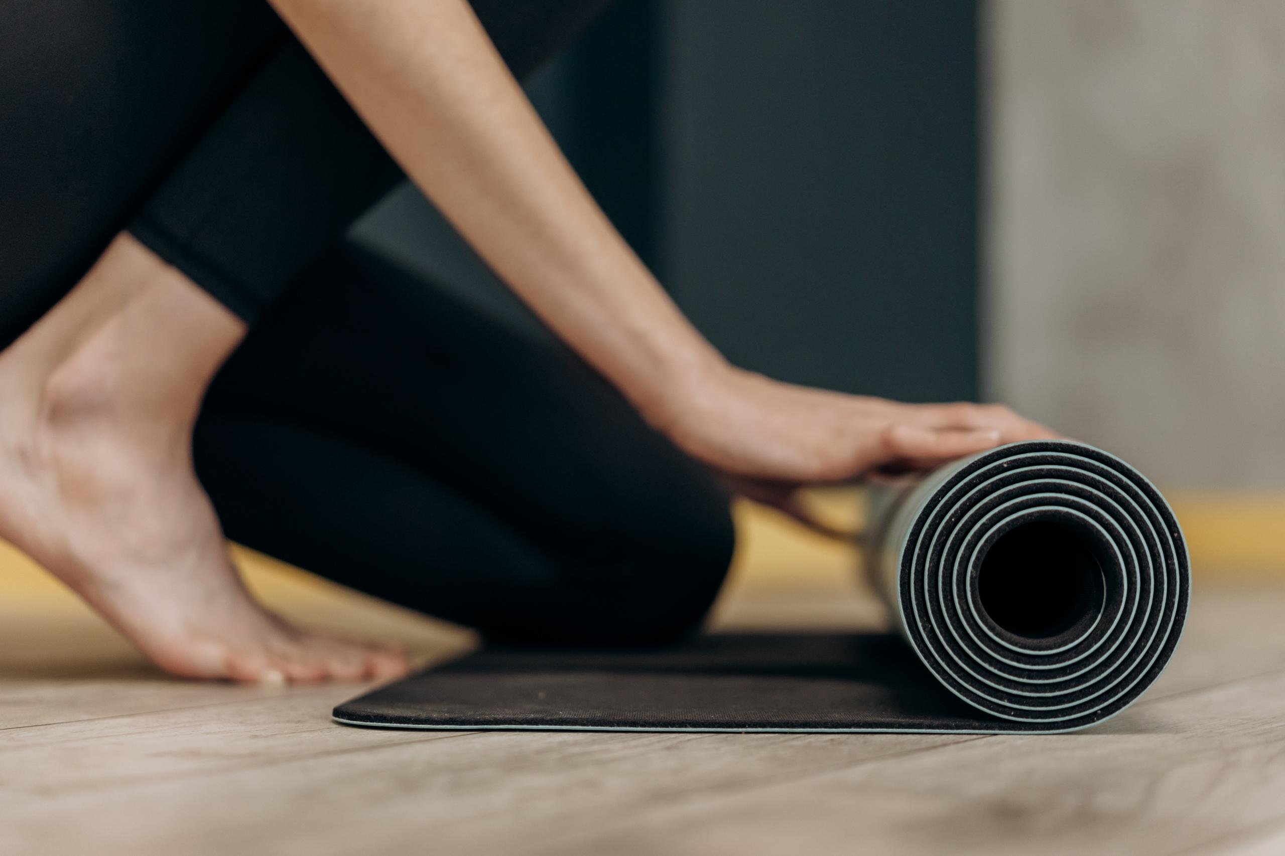 woman rolling out exercise mat to start yoga workout