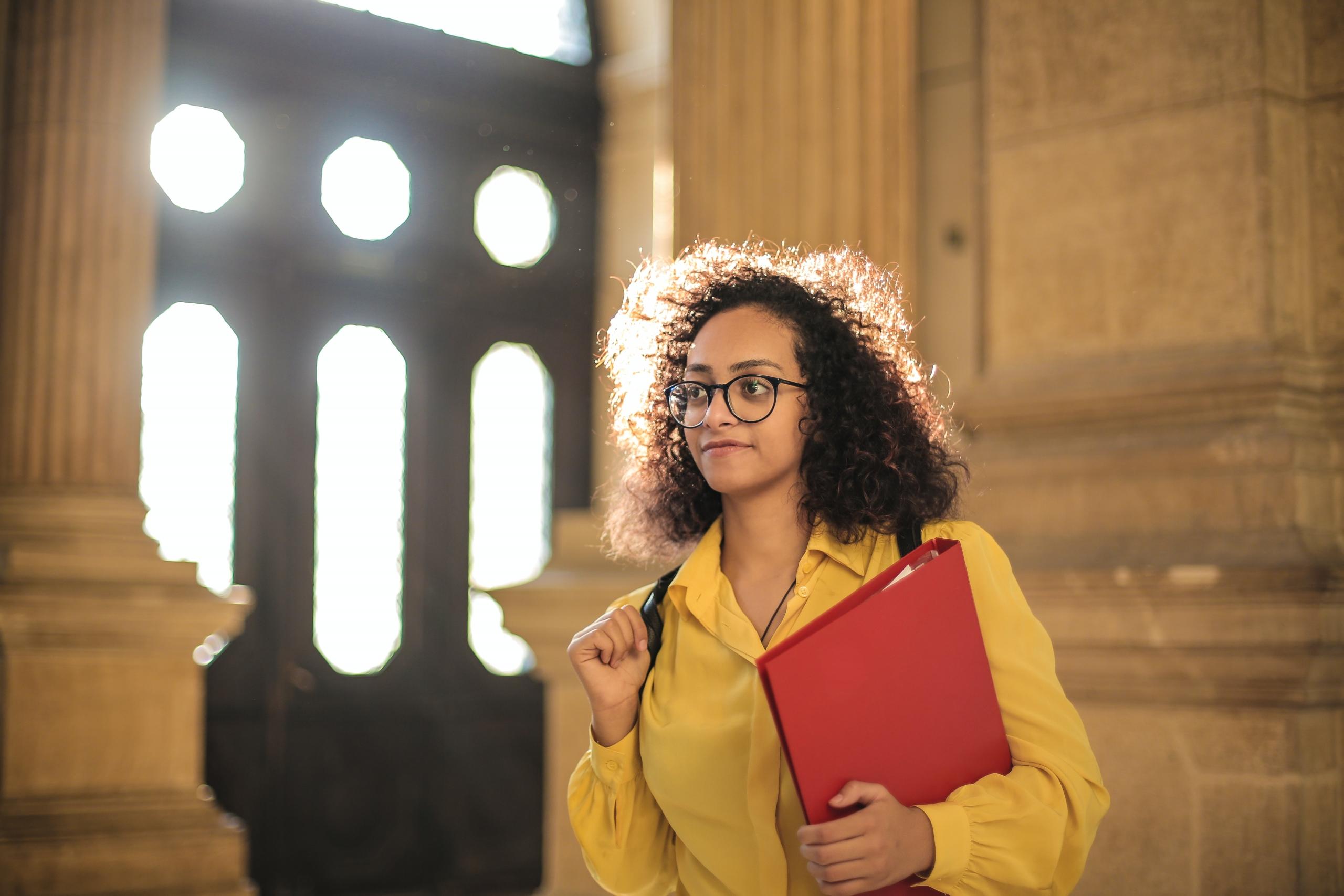 girl wearing backpack and carrying binder