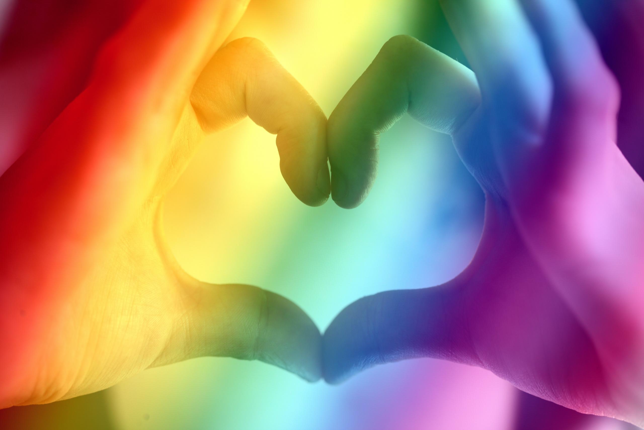 pride coloured lights and hands creating a heart shape