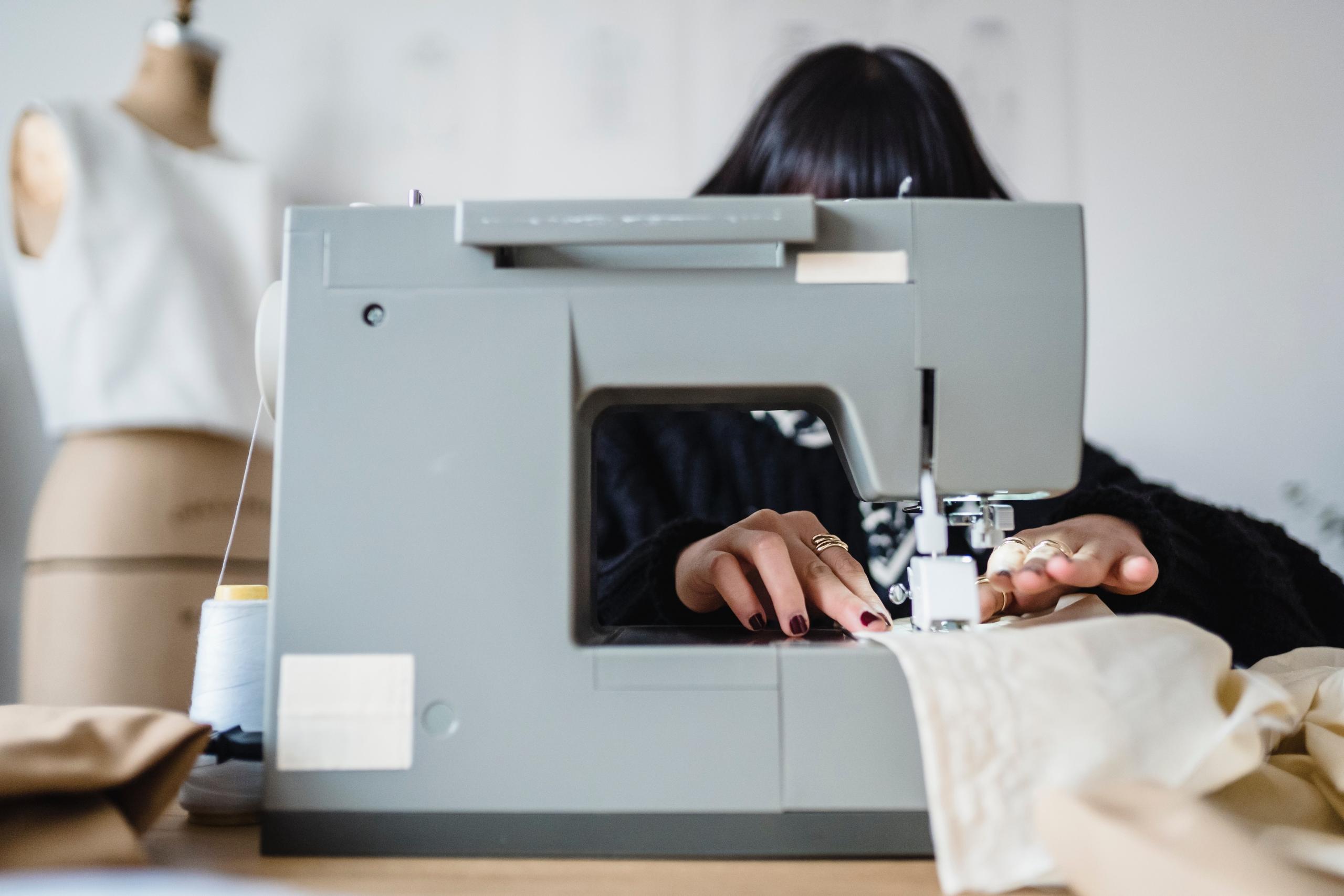 student sewing fabric using sewing machine