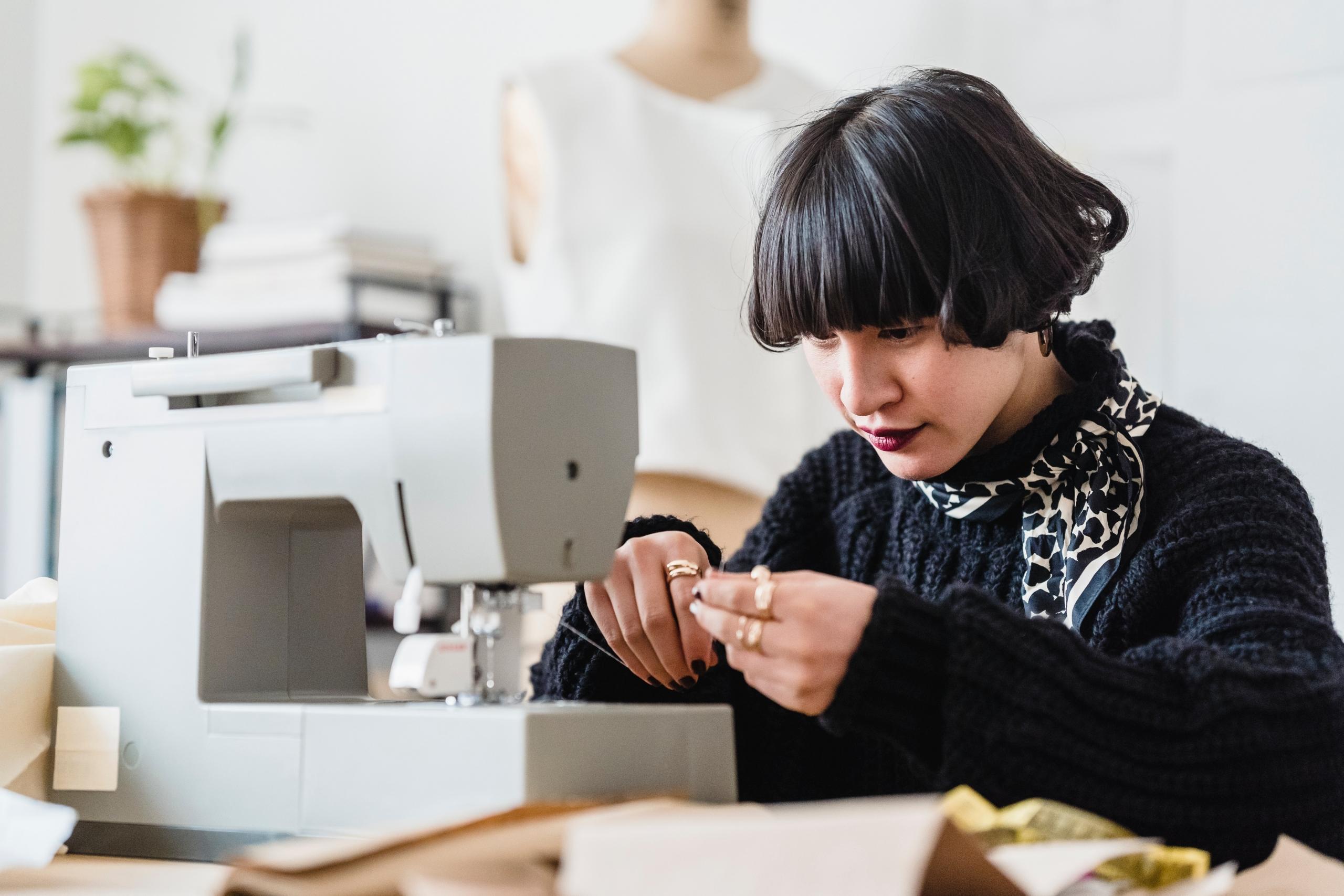 student trying to thread cotton on sewing machine