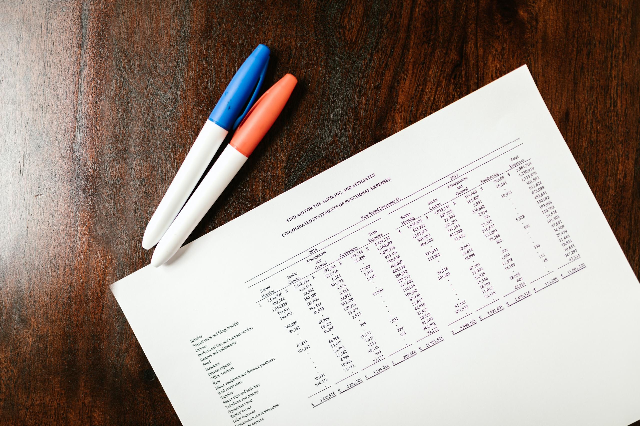 markers placed on tabletop next to financial records