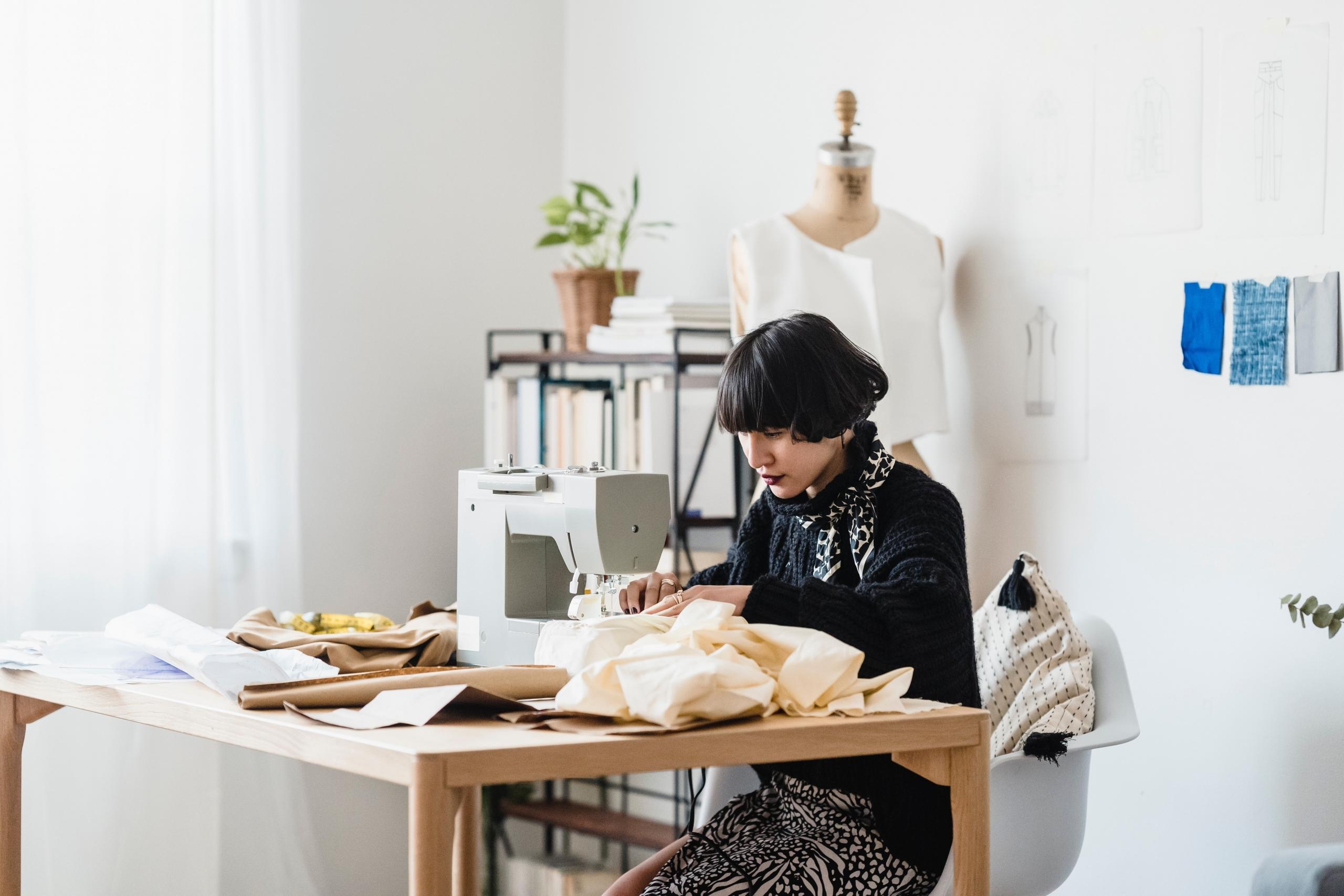 designer in studio sewing clothes with sewing machine