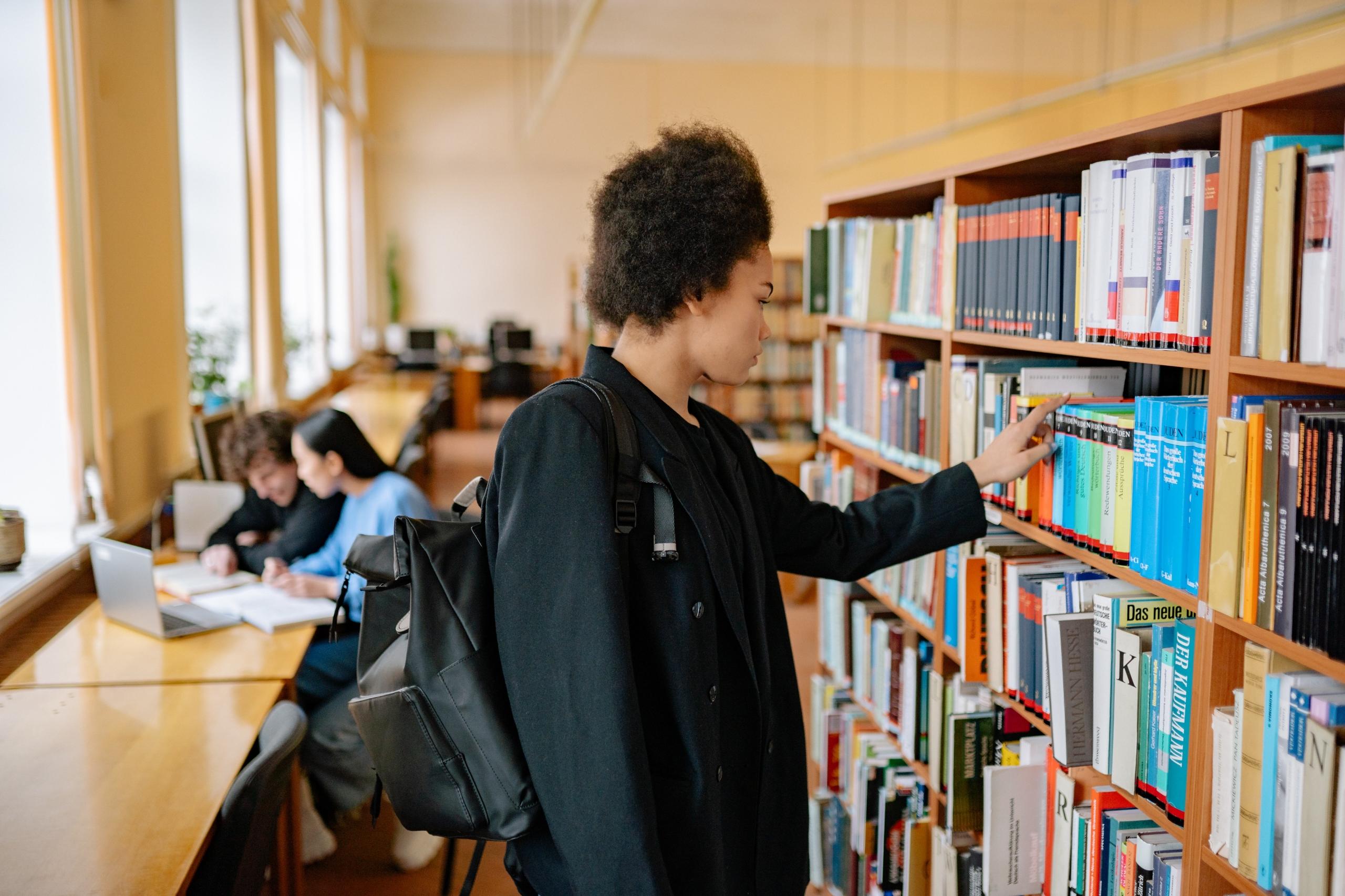 woman consulting books on library shelves