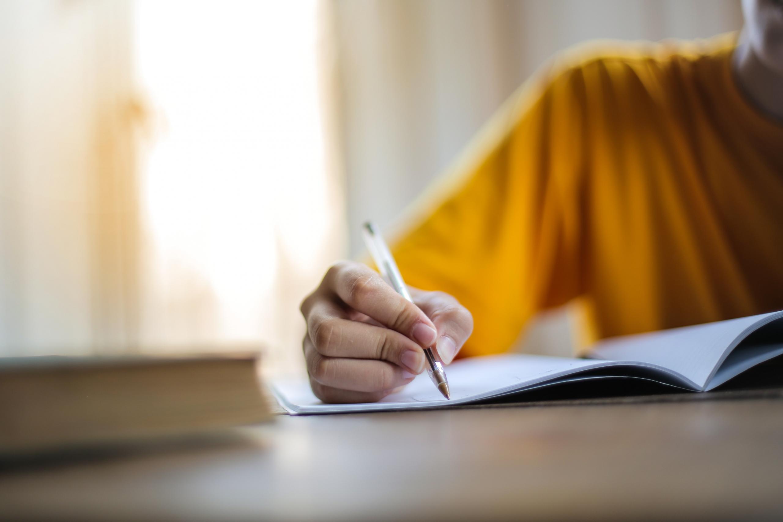person writing in notebook with a pen
