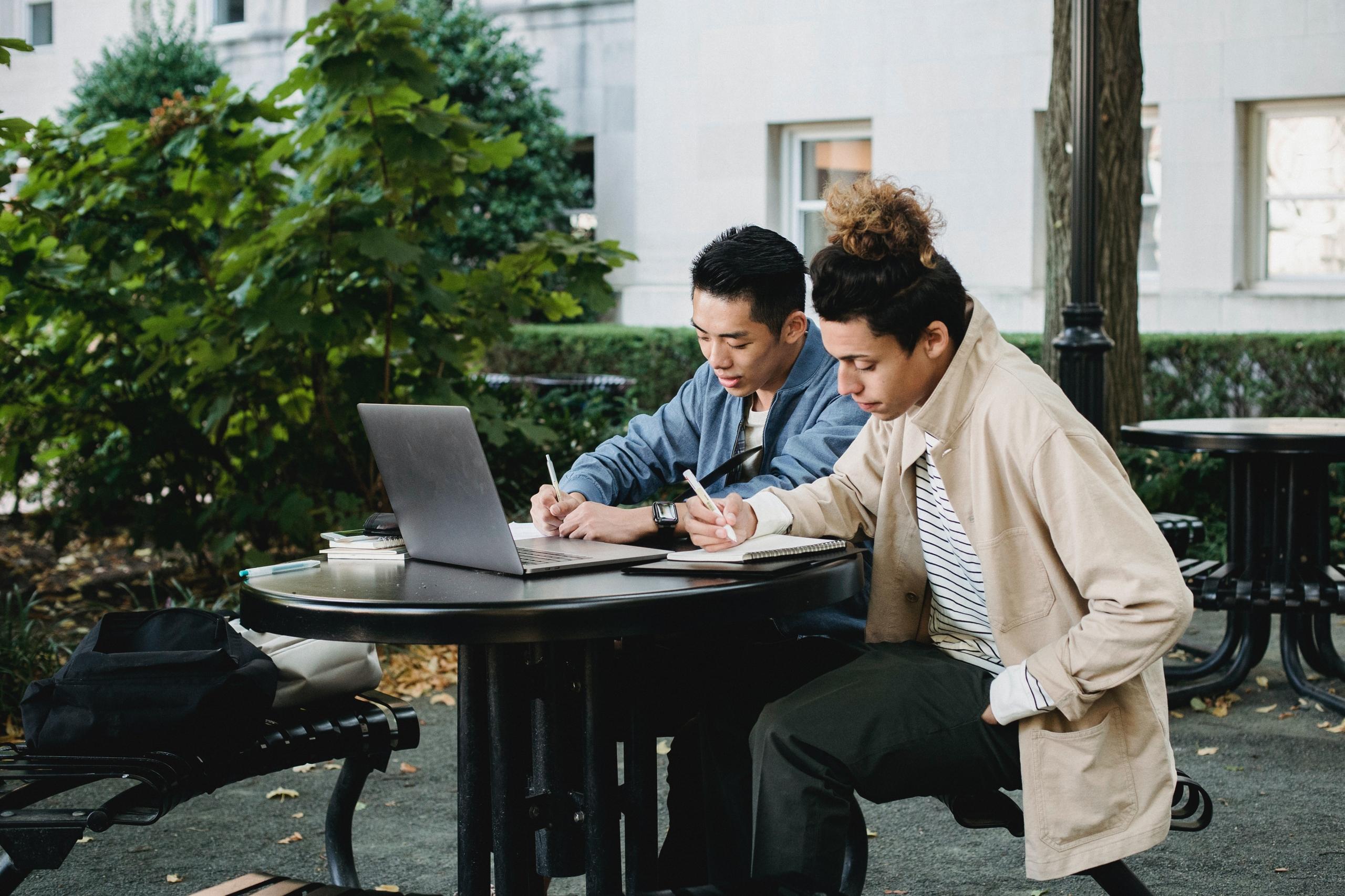 two students studying together using laptop