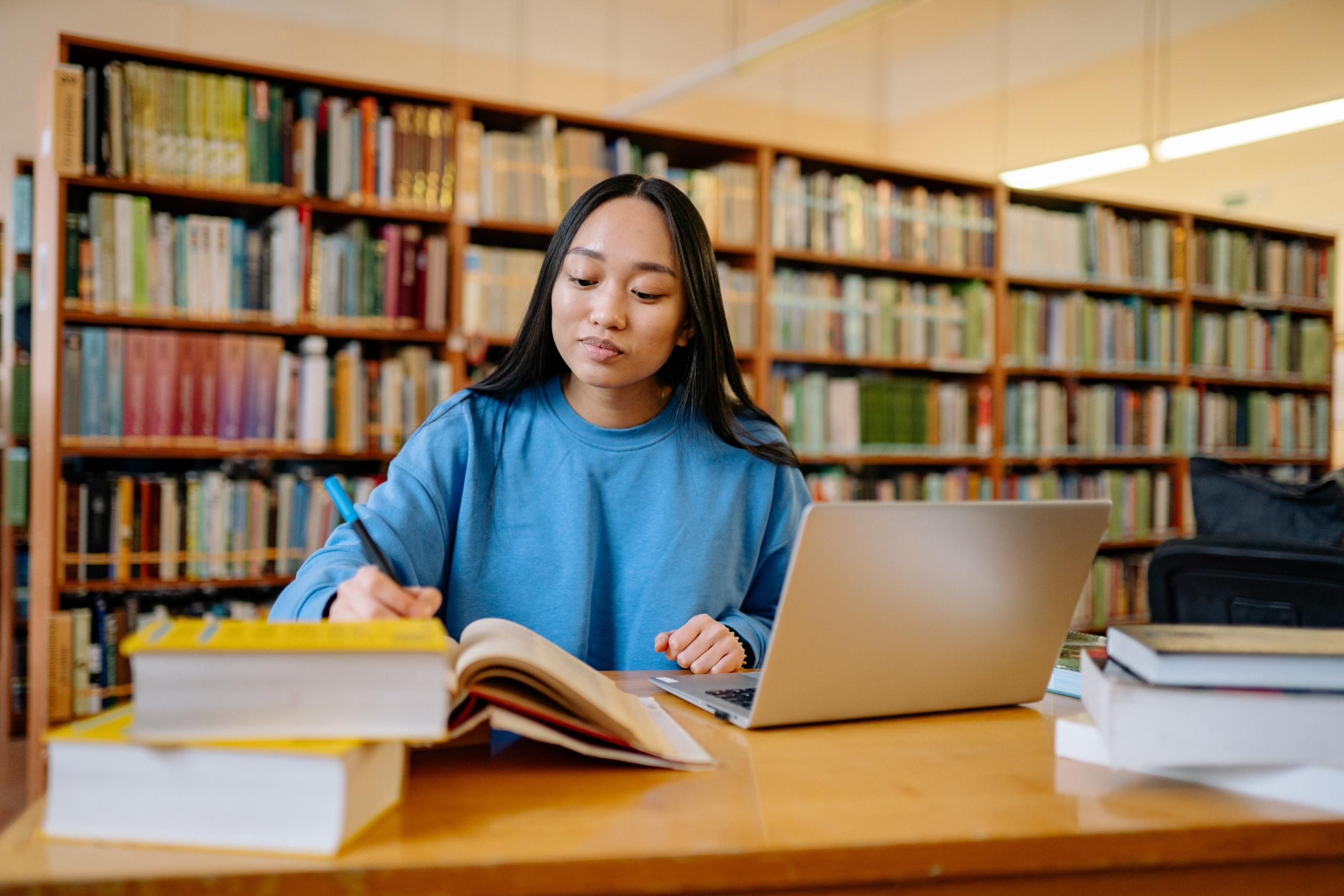 woman in blue long sleeve sweatshirt sitting at a table writing