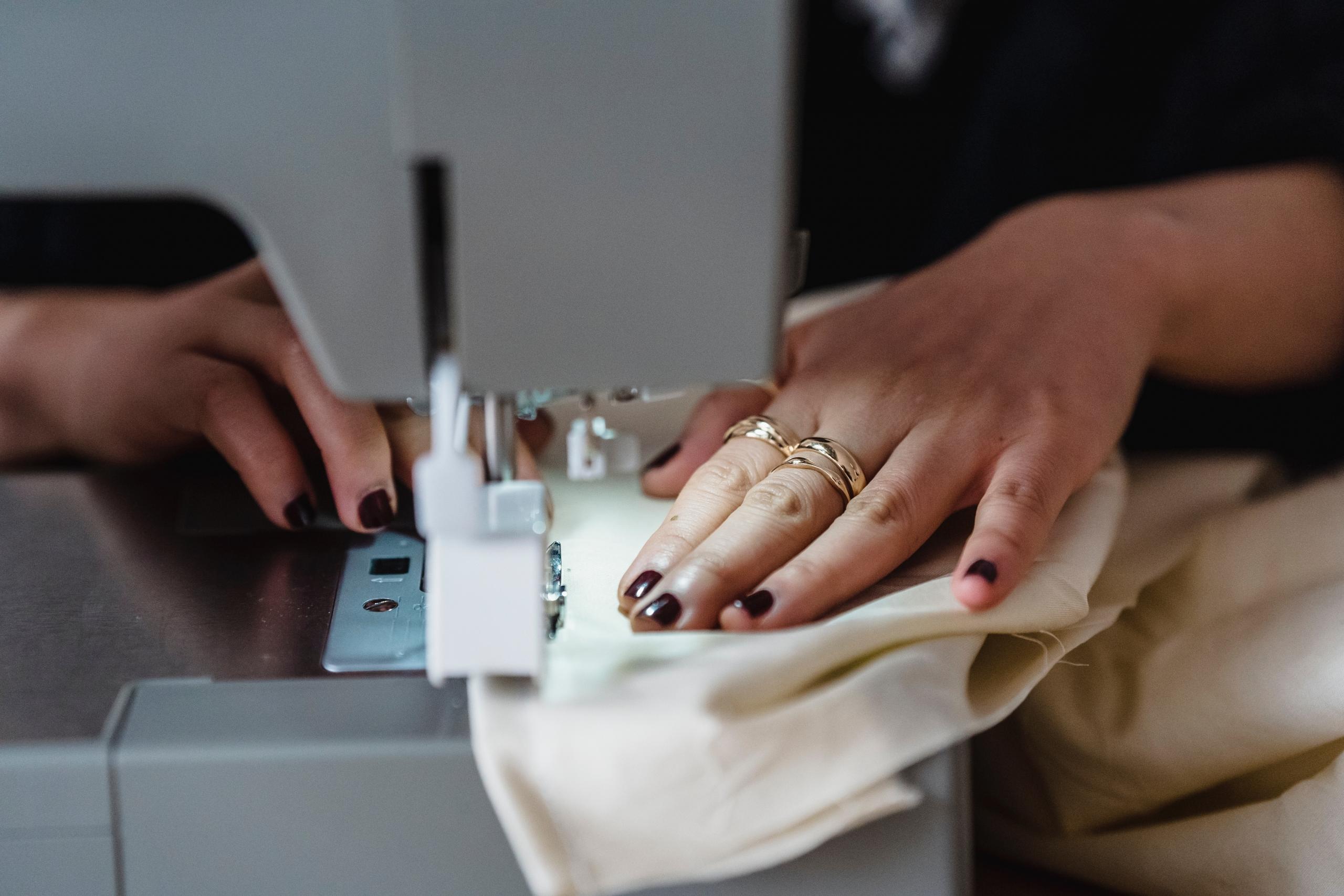 close up of woman's hands stitching fabric with sewing machine