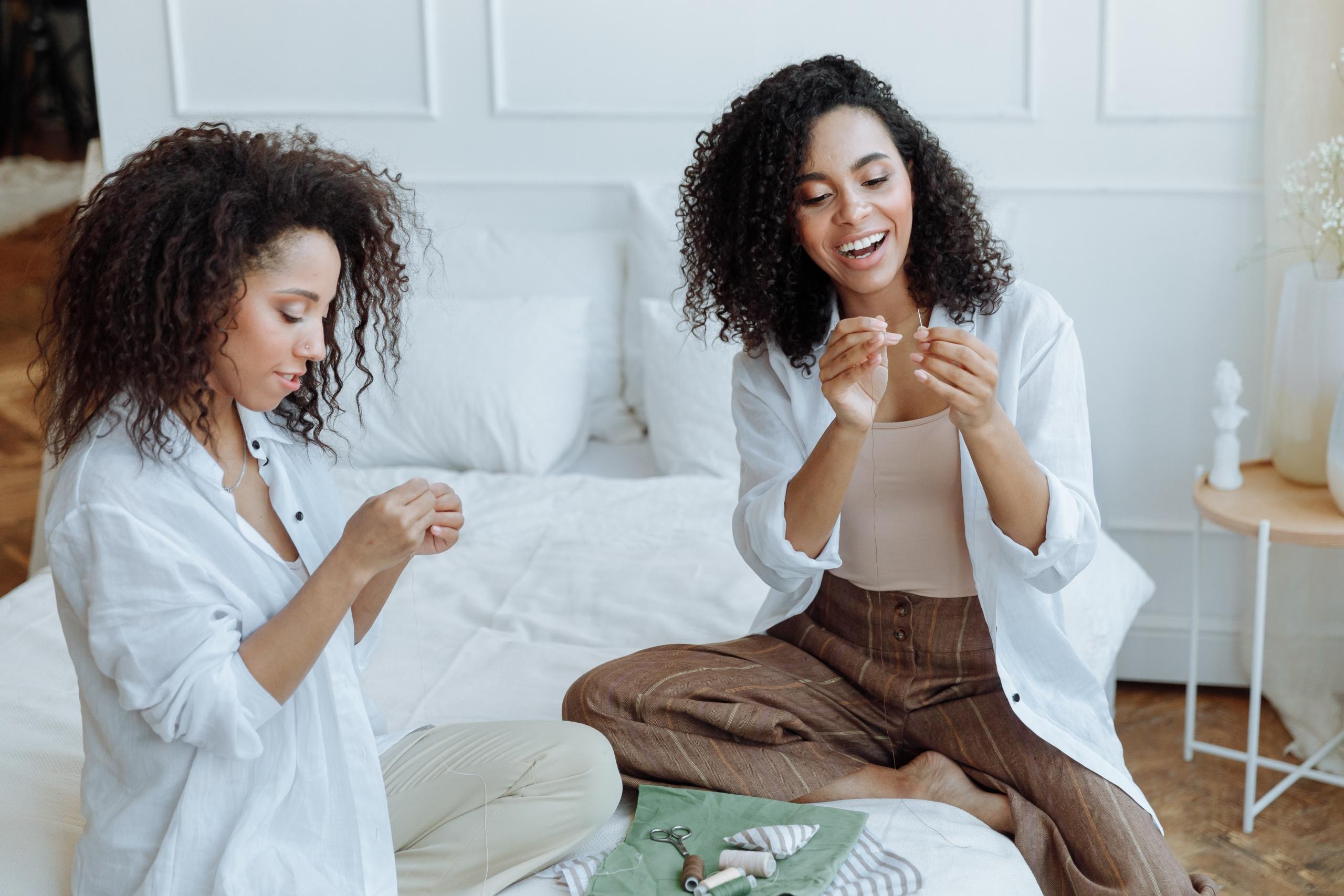 two friends threading sewing needles