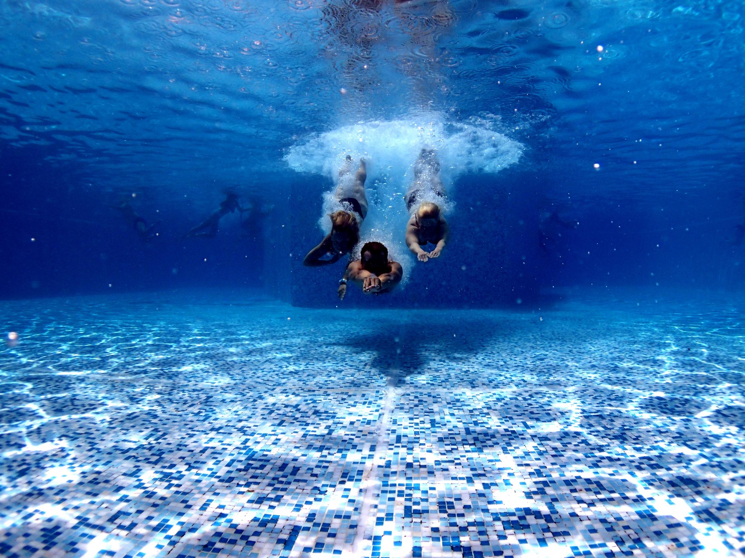 three underwater swimmers in a pool