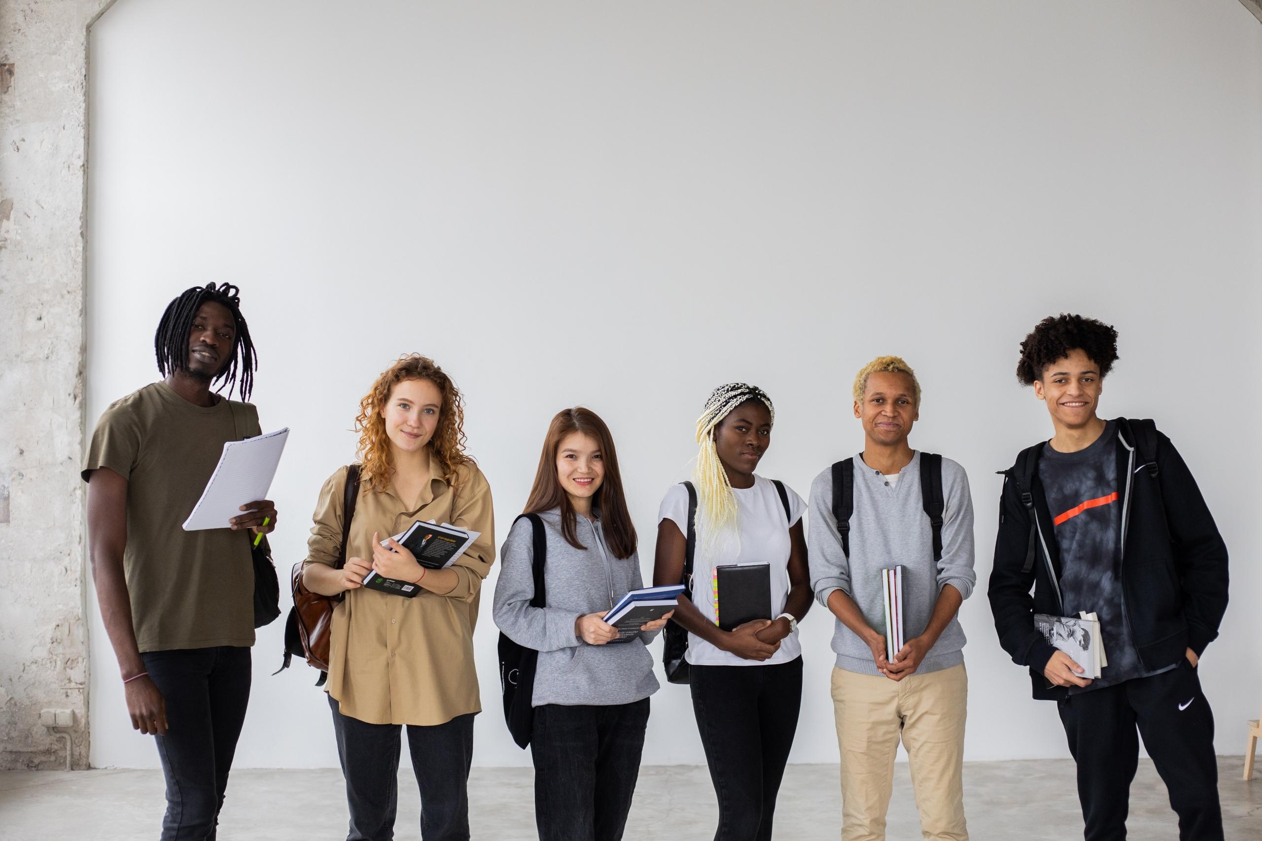 group of students lined up carrying books and paper