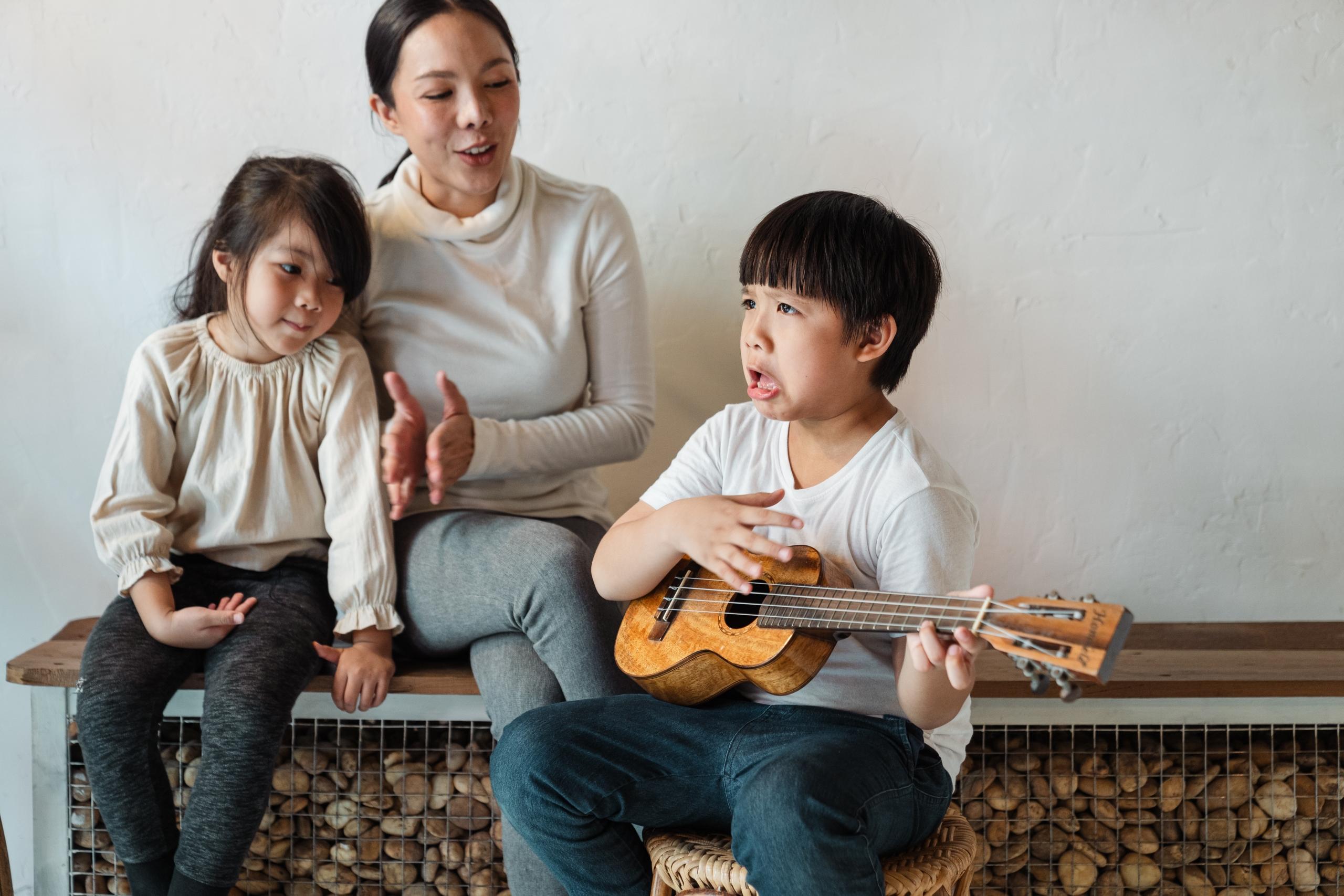 mom and children singing as boy plays guitar