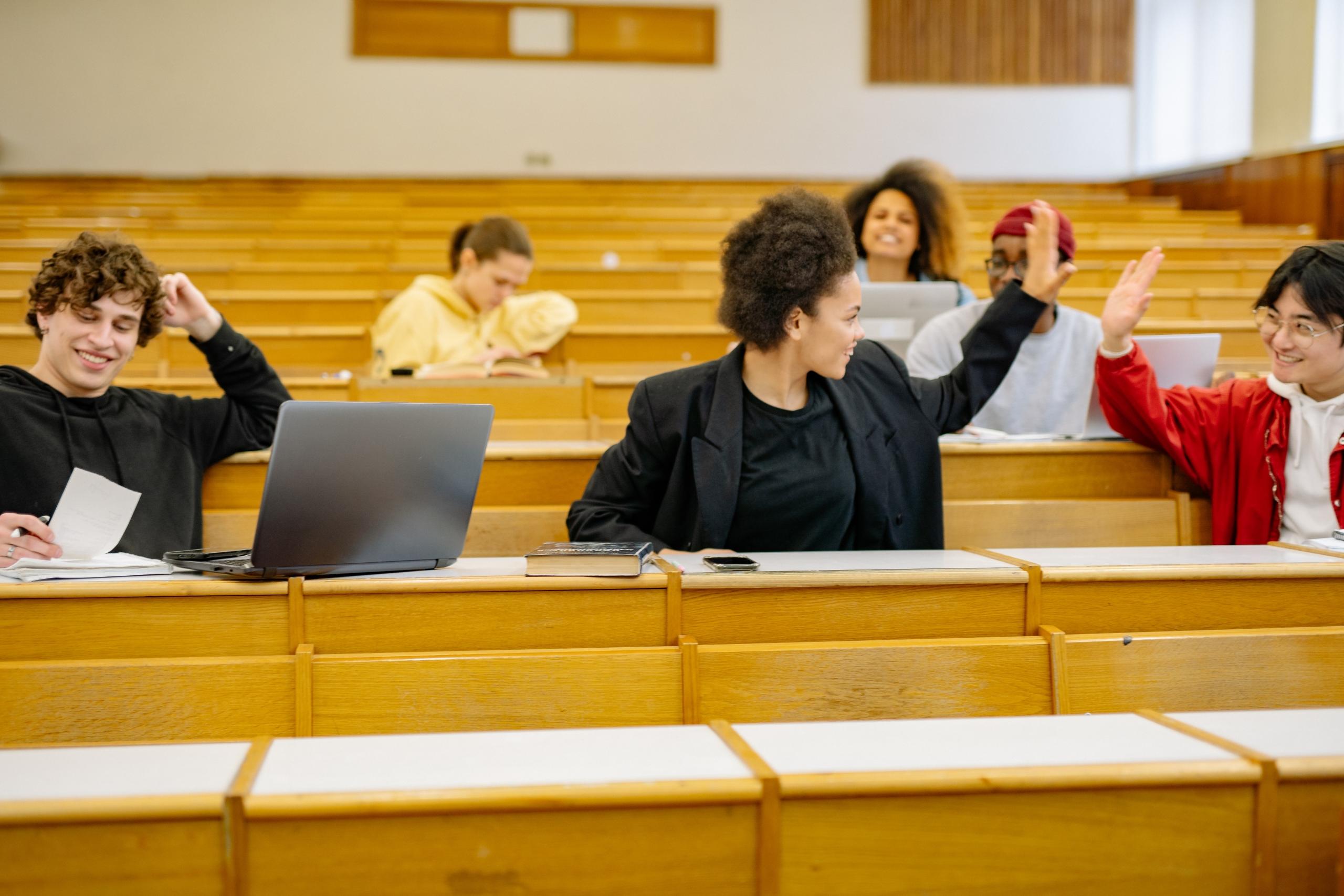 teens high-fiving each other in a university classroom