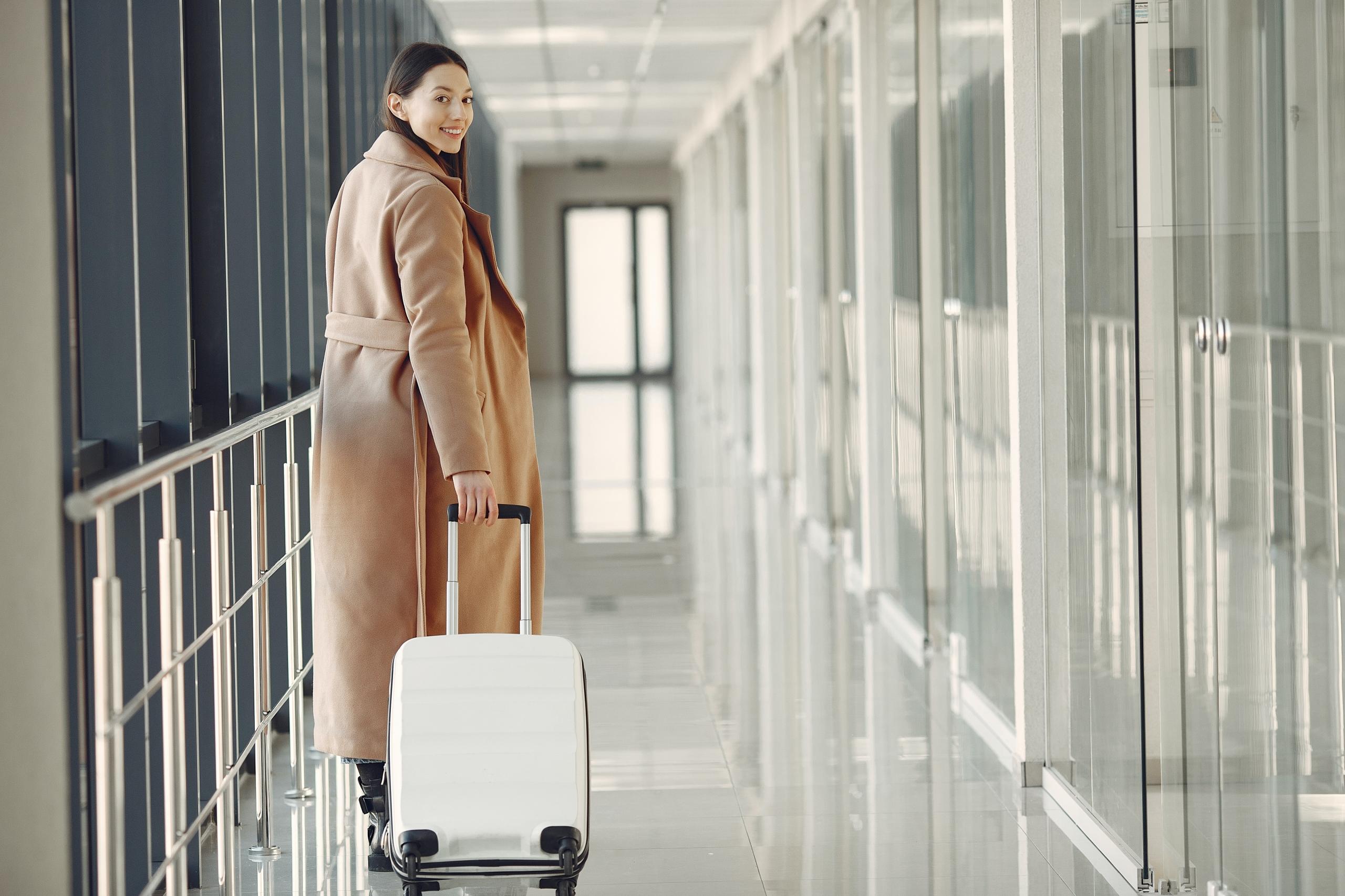 traveller pulling carry-on bag down airport corridor