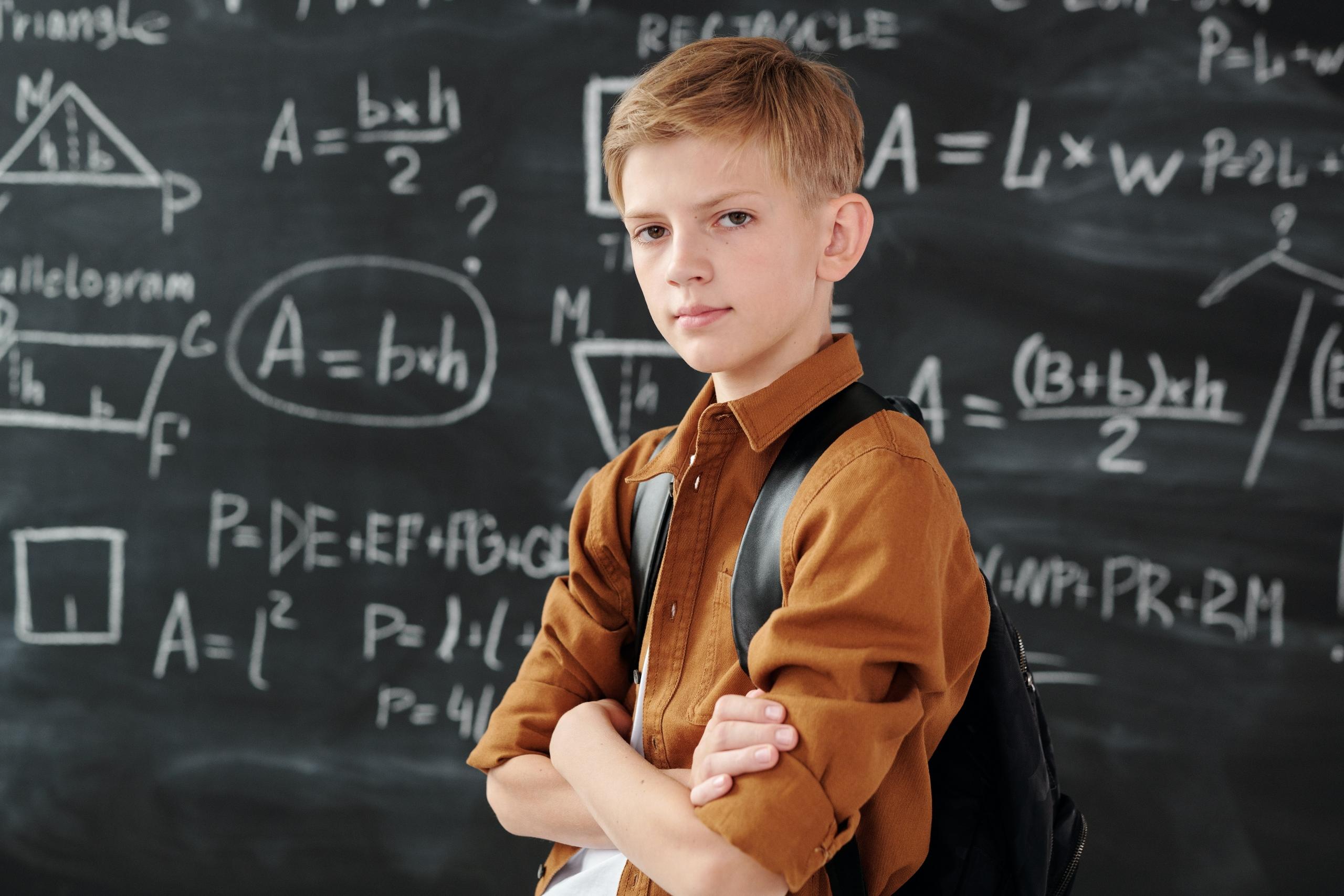 student in class with mathematics equations written on board