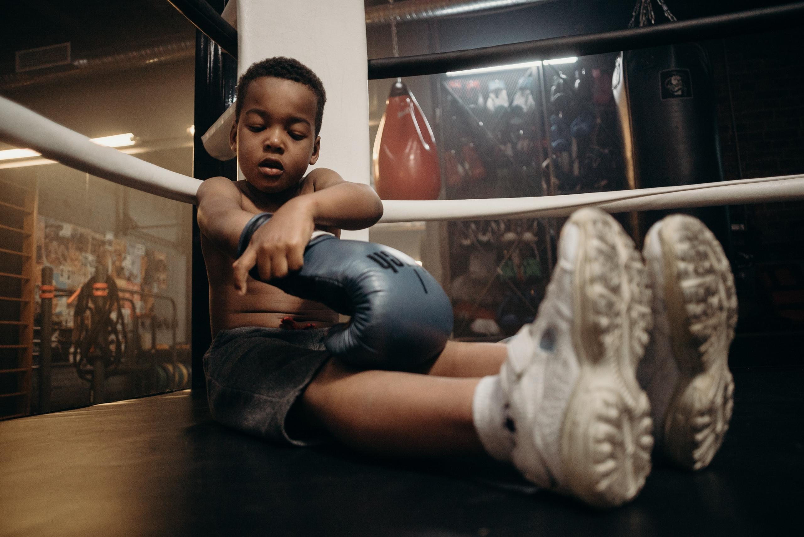 small boy wearing boxing gloves in gym