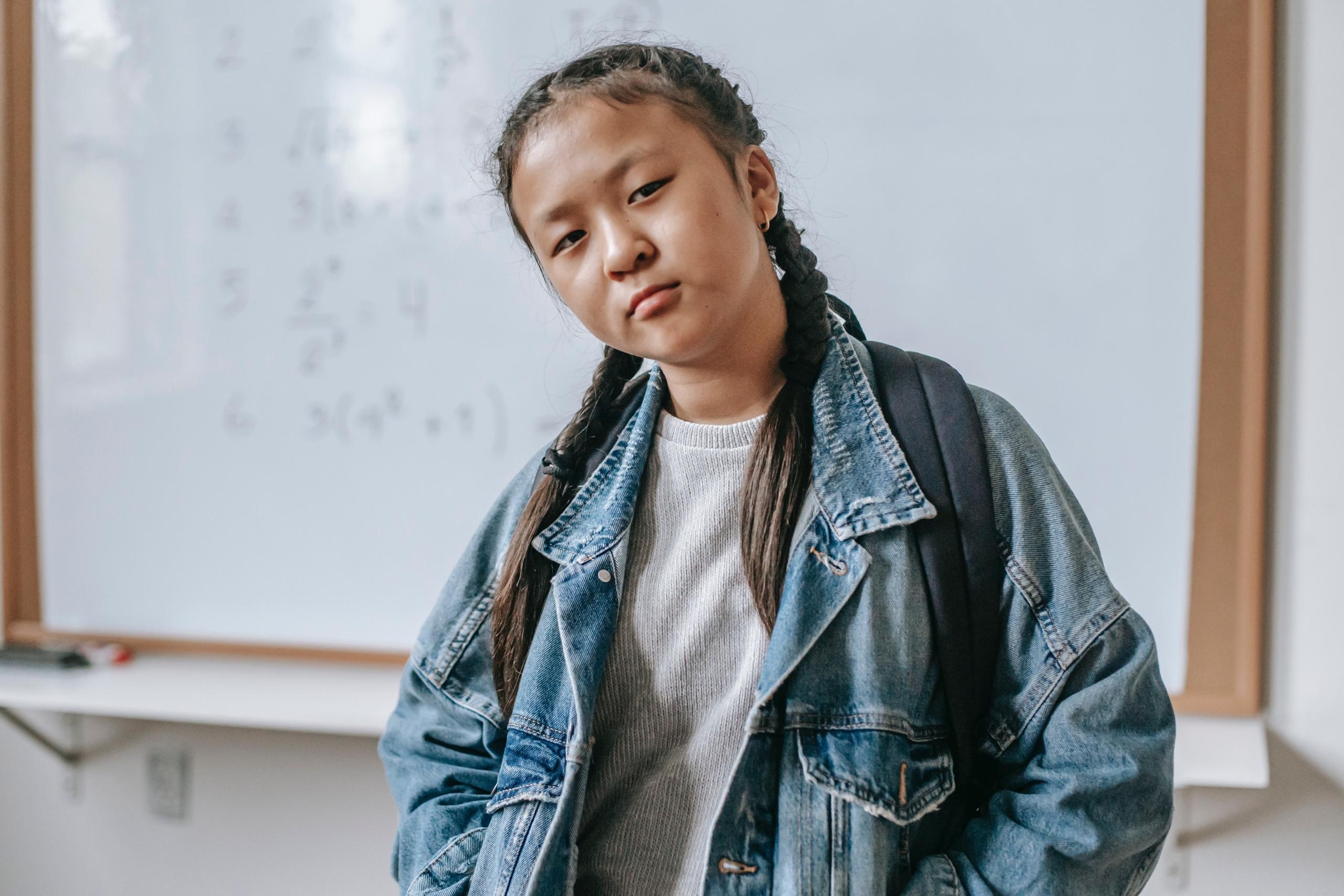board filled with maths problems in background behind student