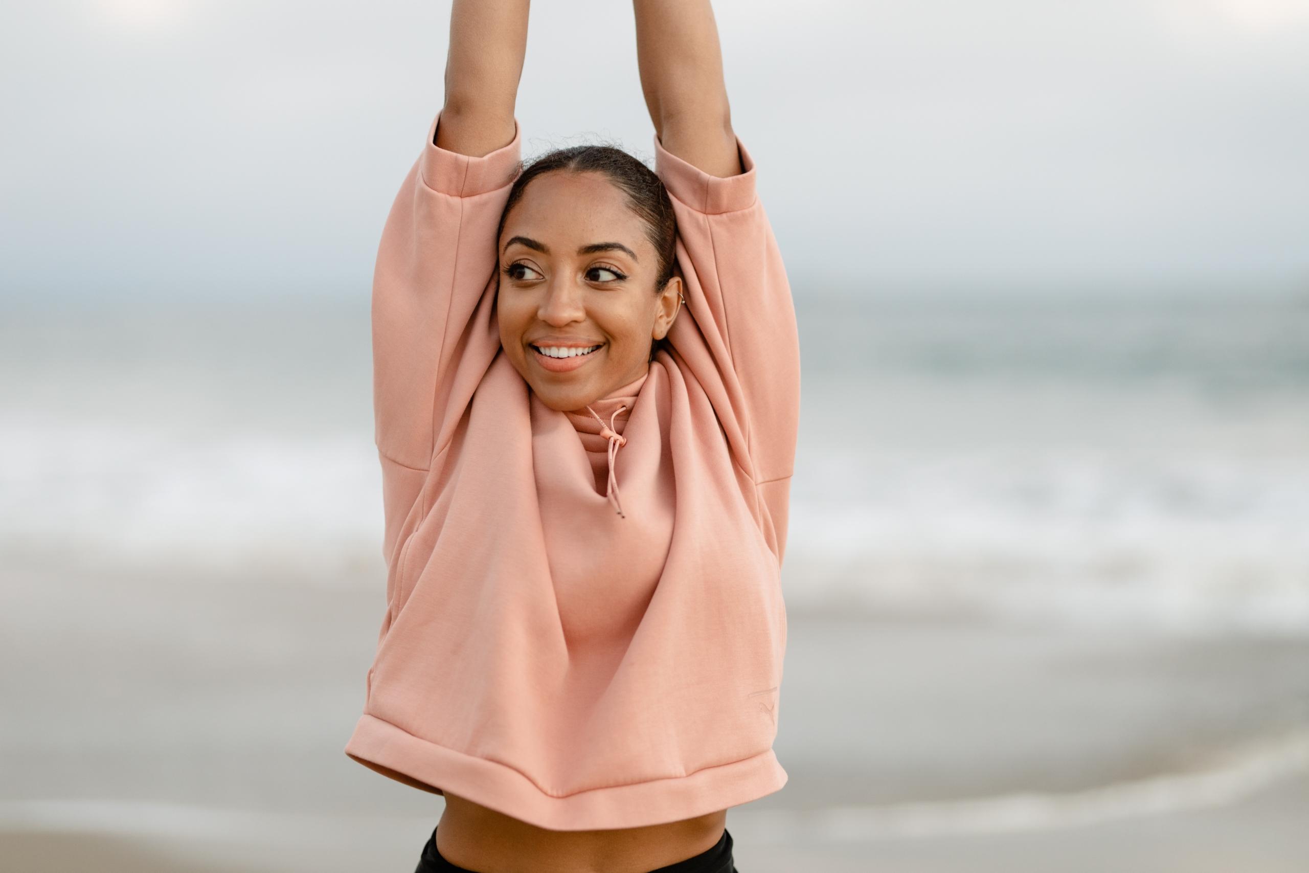 sportswoman at the beach lifting arms in the air