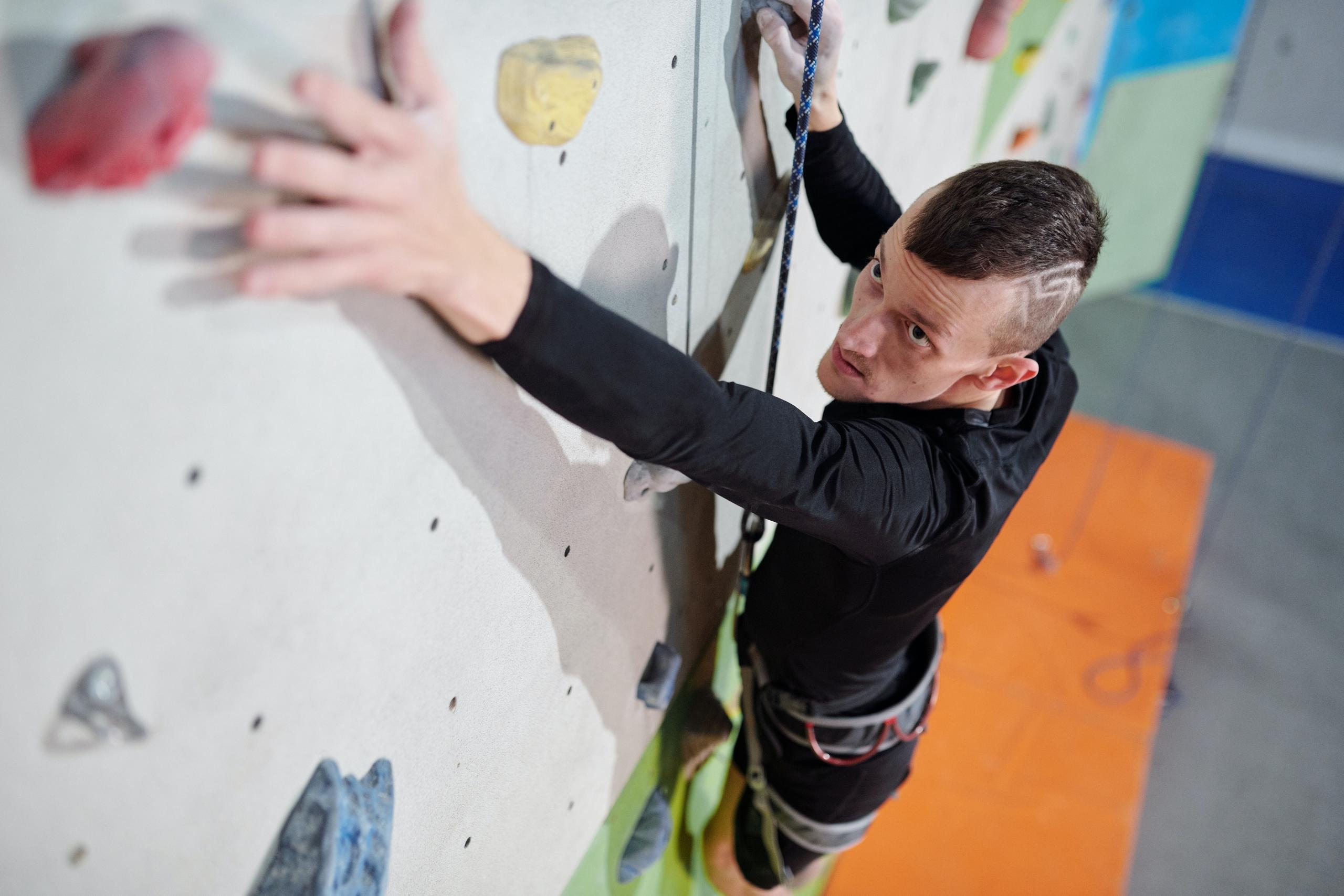 man in black outfit doing indoor climbing