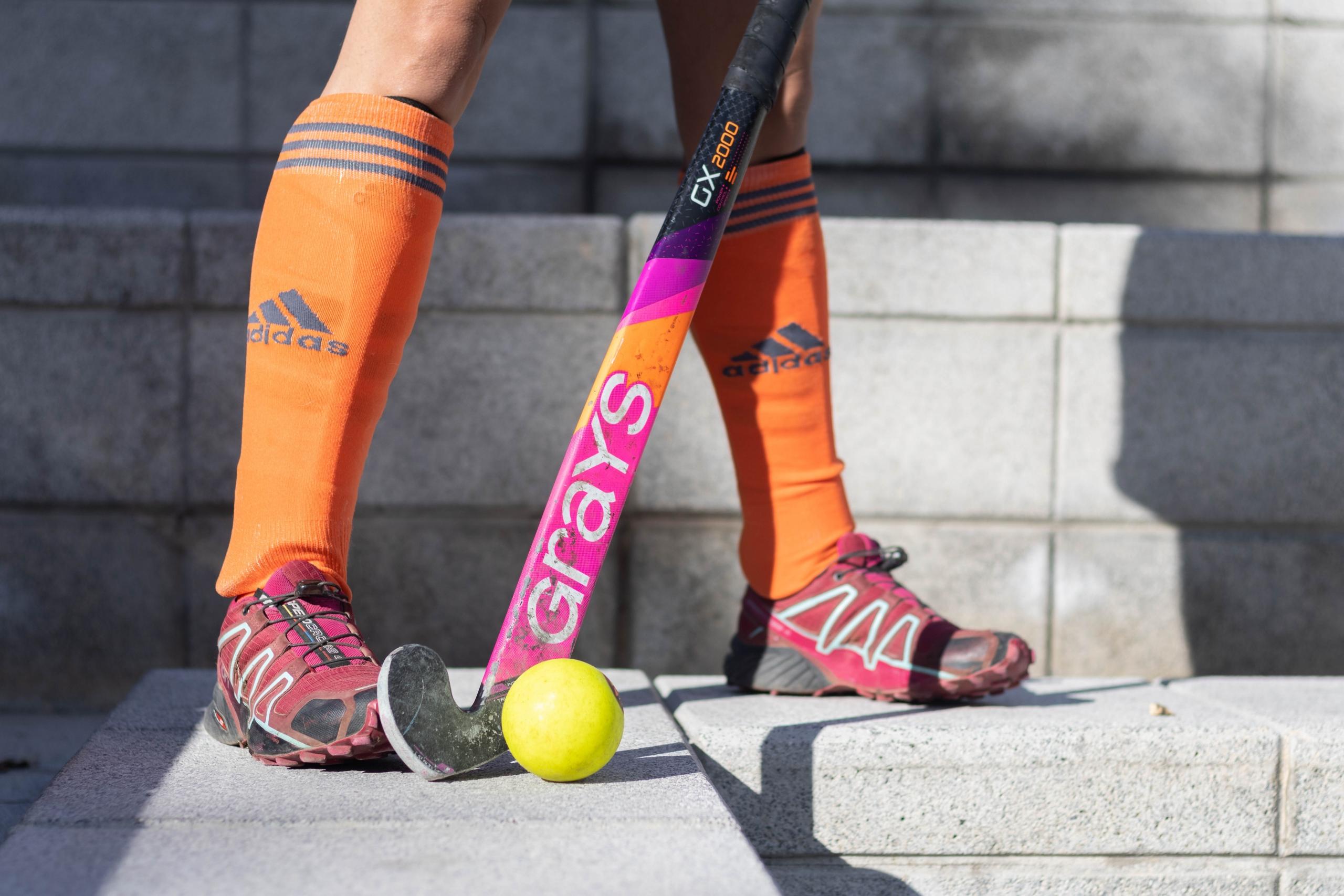 close up of pink hockey stick and yellow hockey ball