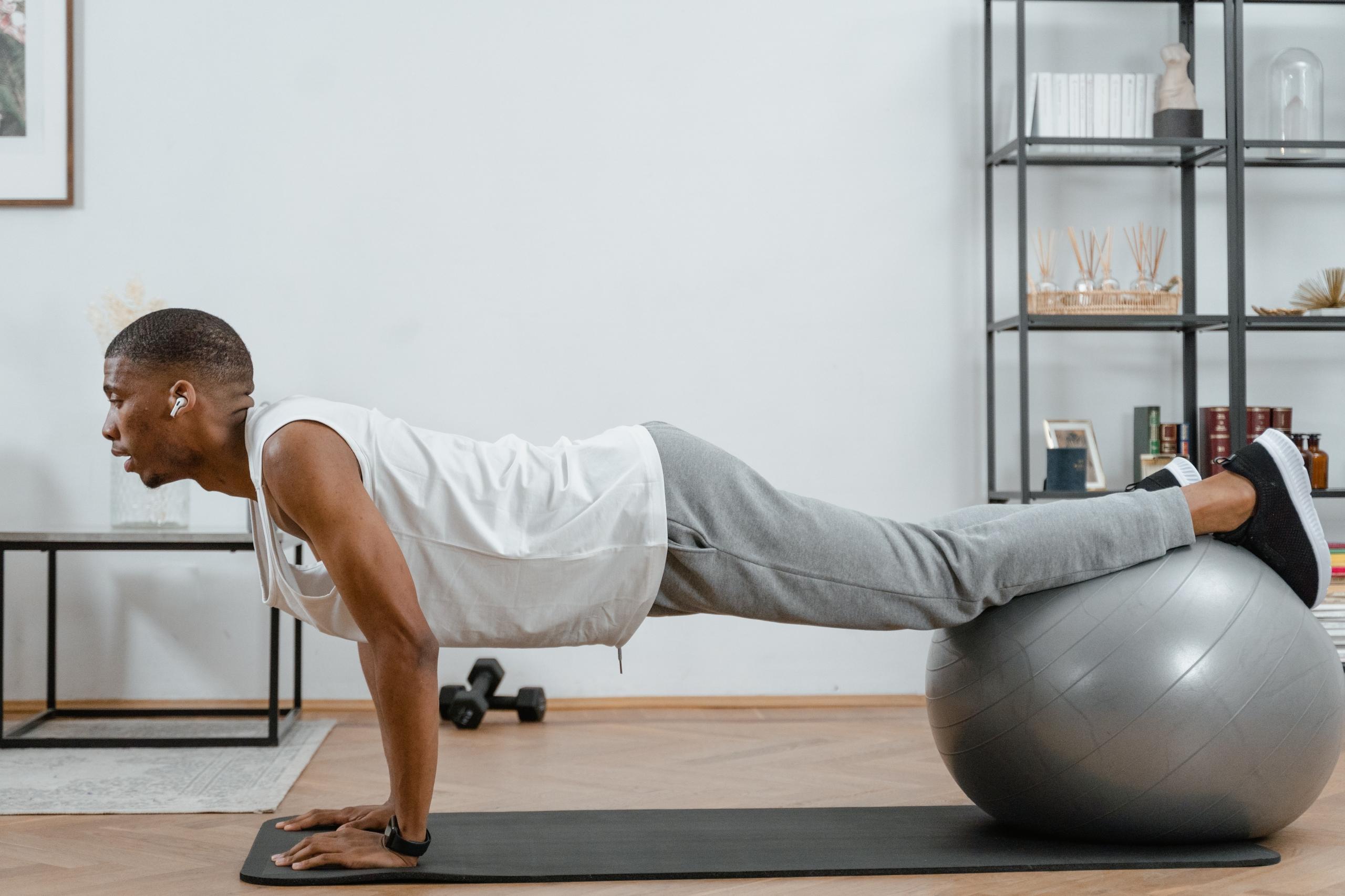 person doing home workout balanced on grey exercise ball