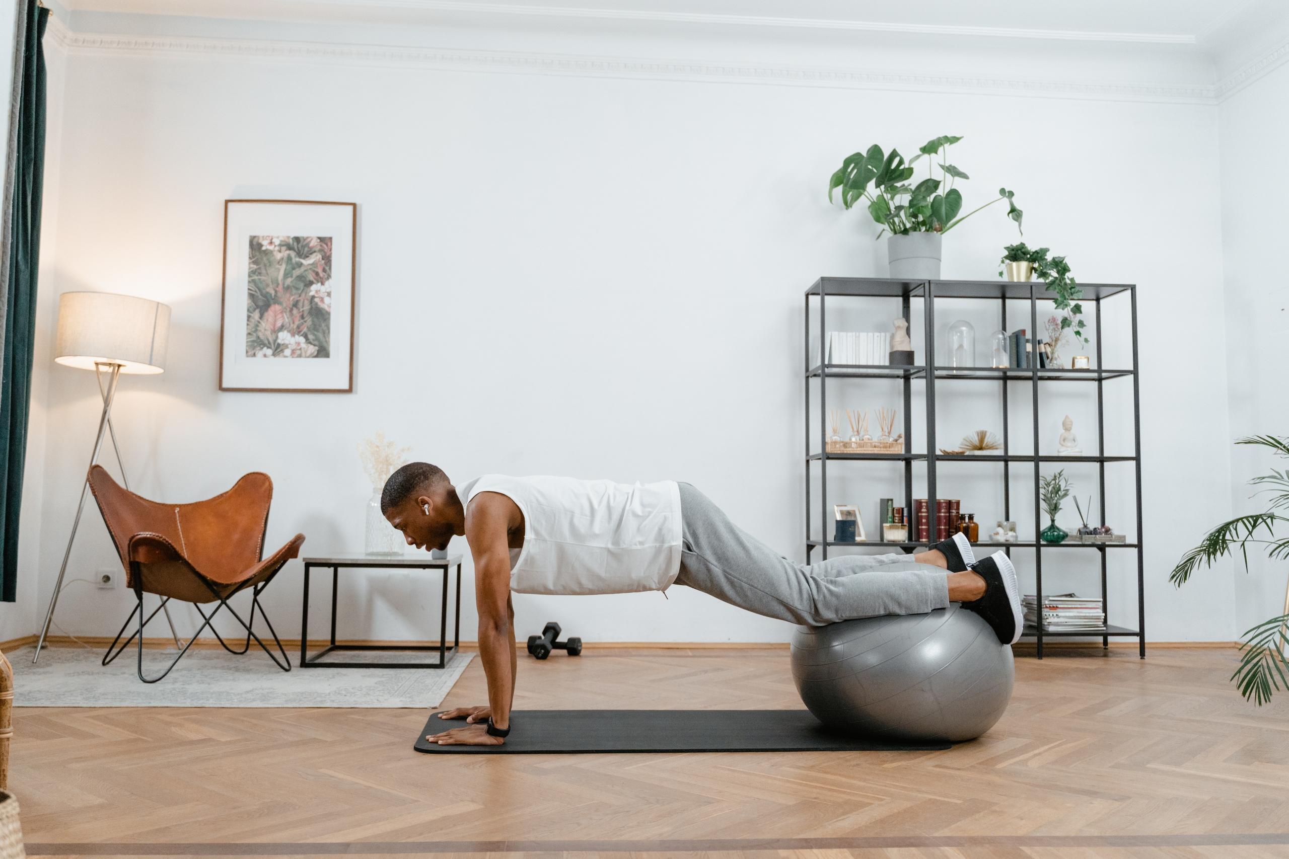 guy doing home workout balanced on big grey exercise ball