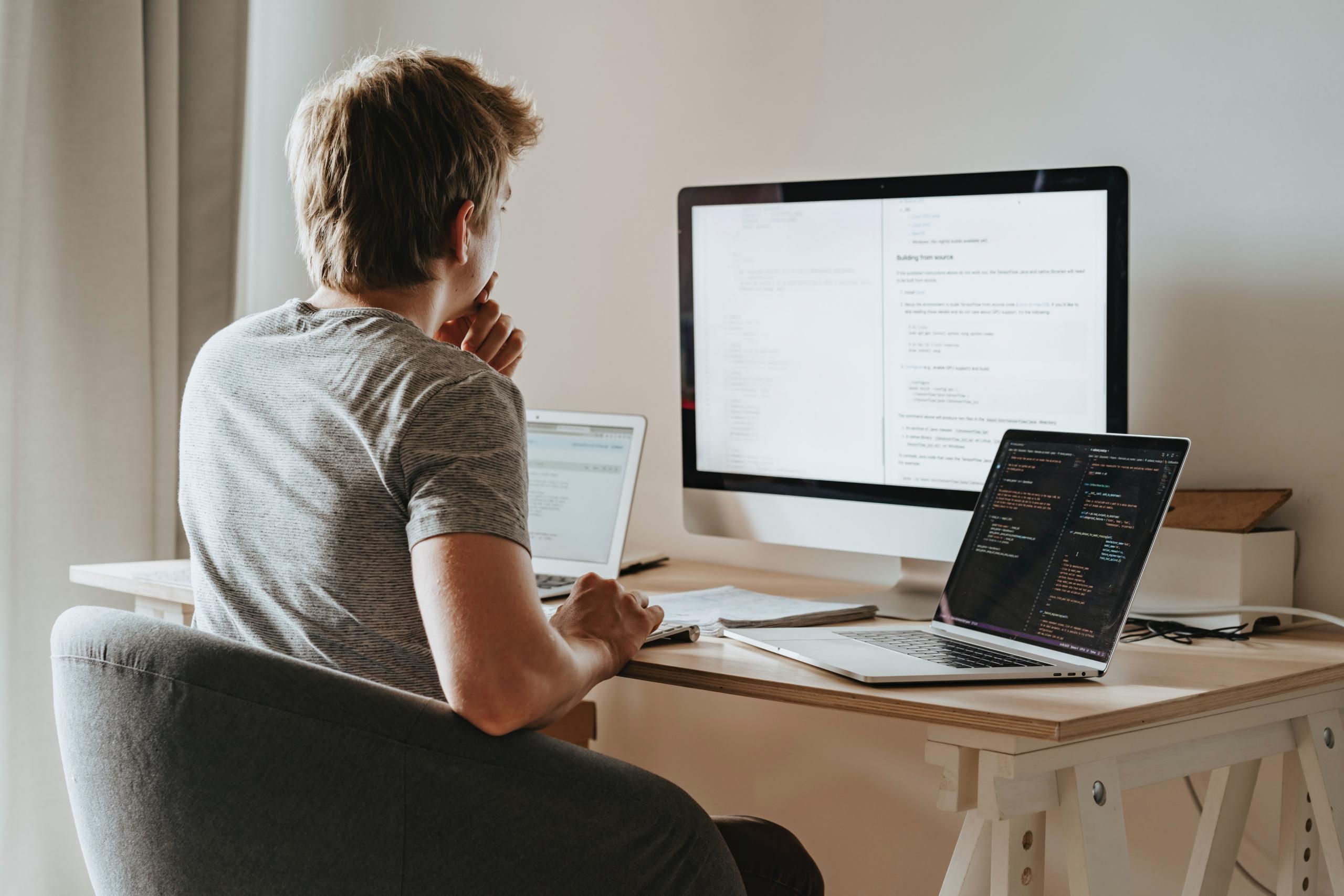 teen using multiple computer screens to analyse data and code