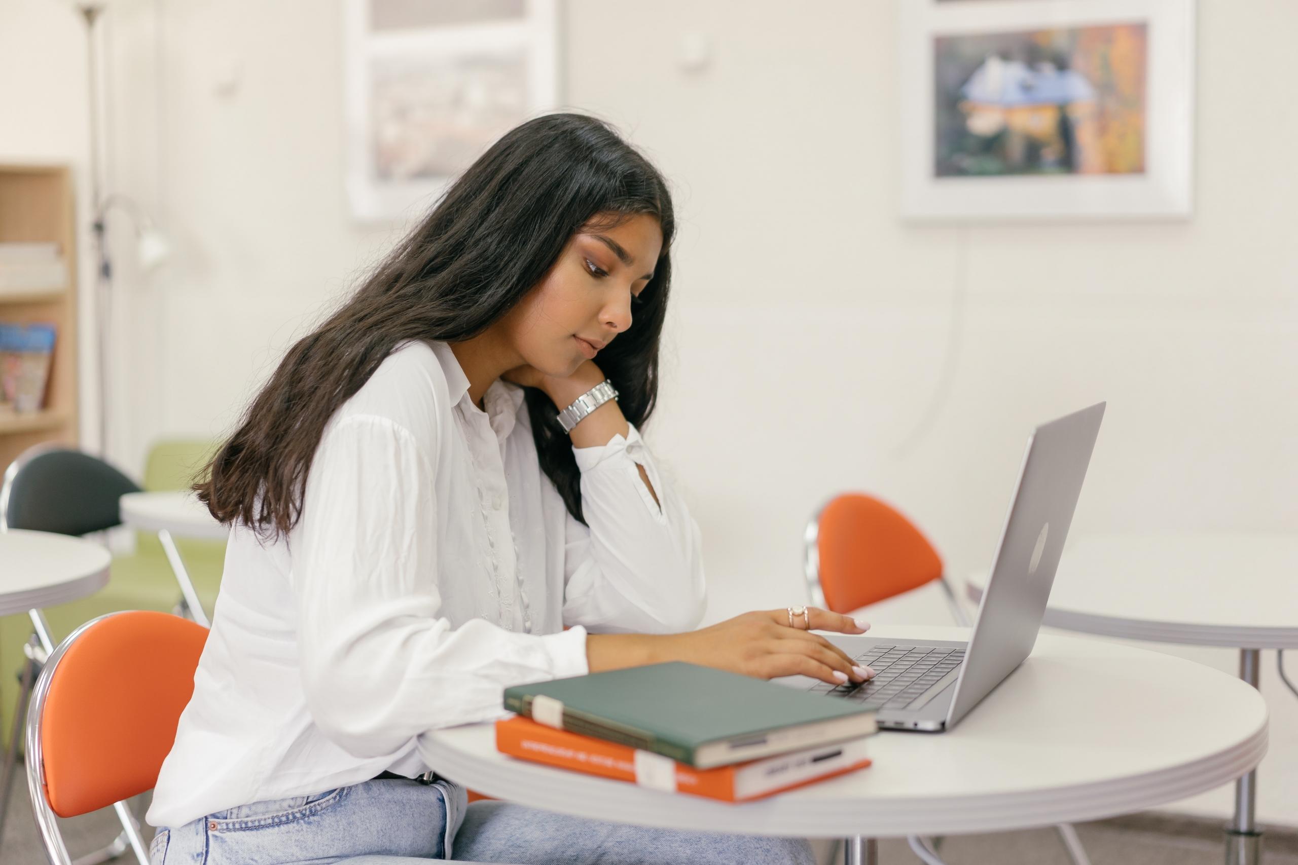 girl studying in library using books and computer