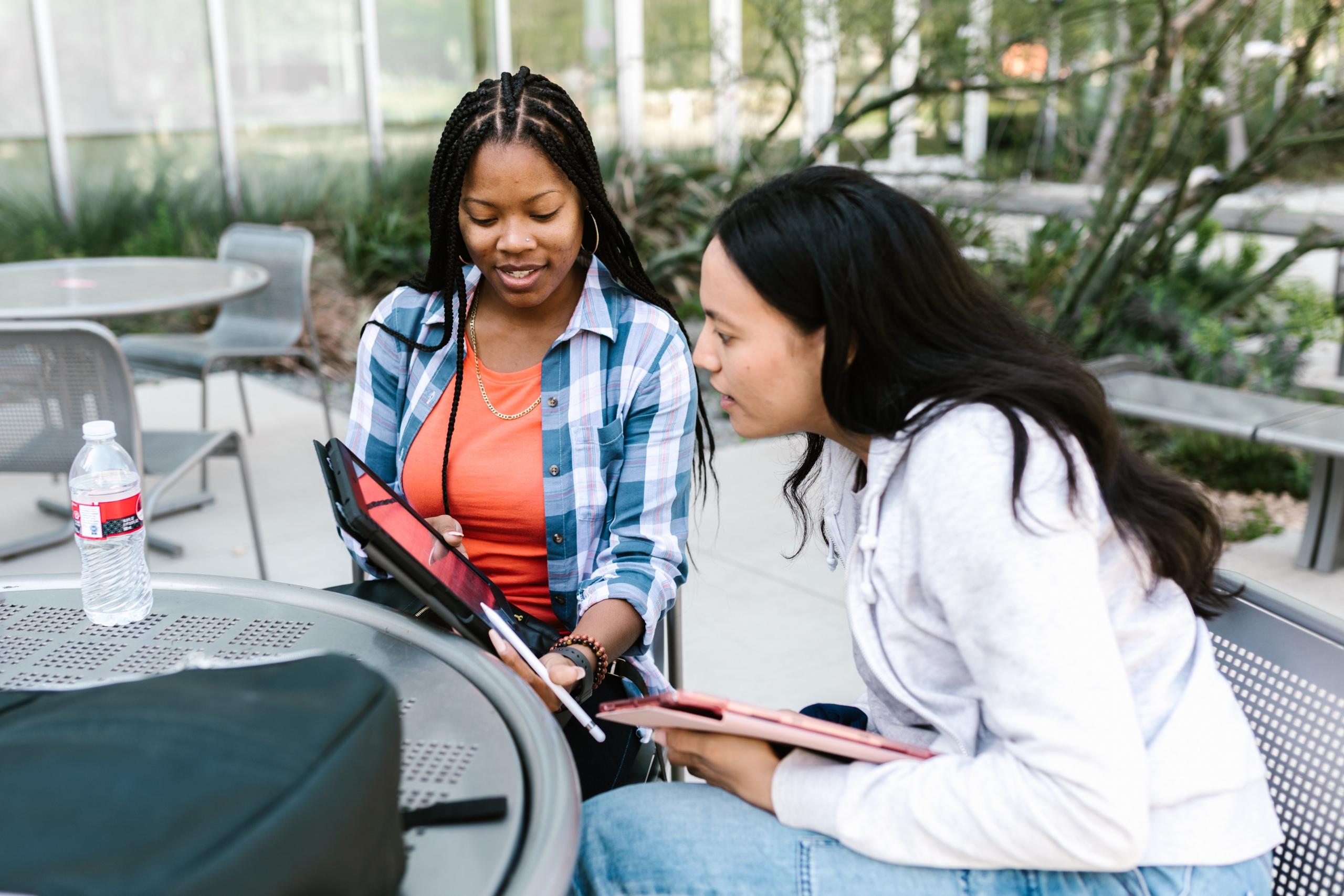 two girls studying together outdoors