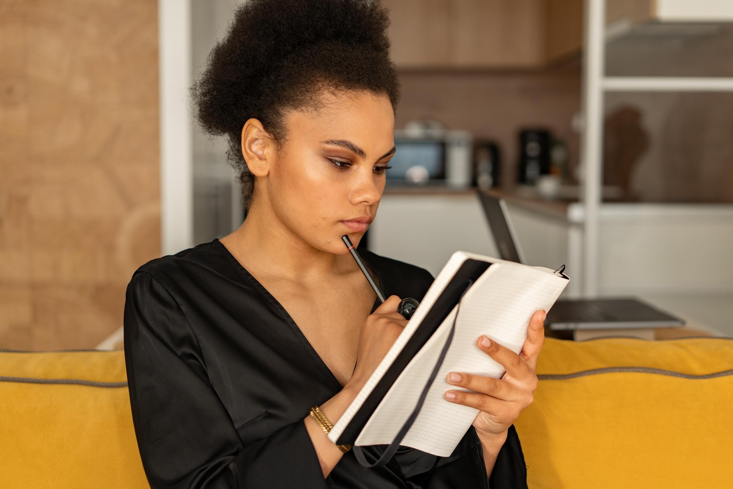 person holding pen to lips and reading notes