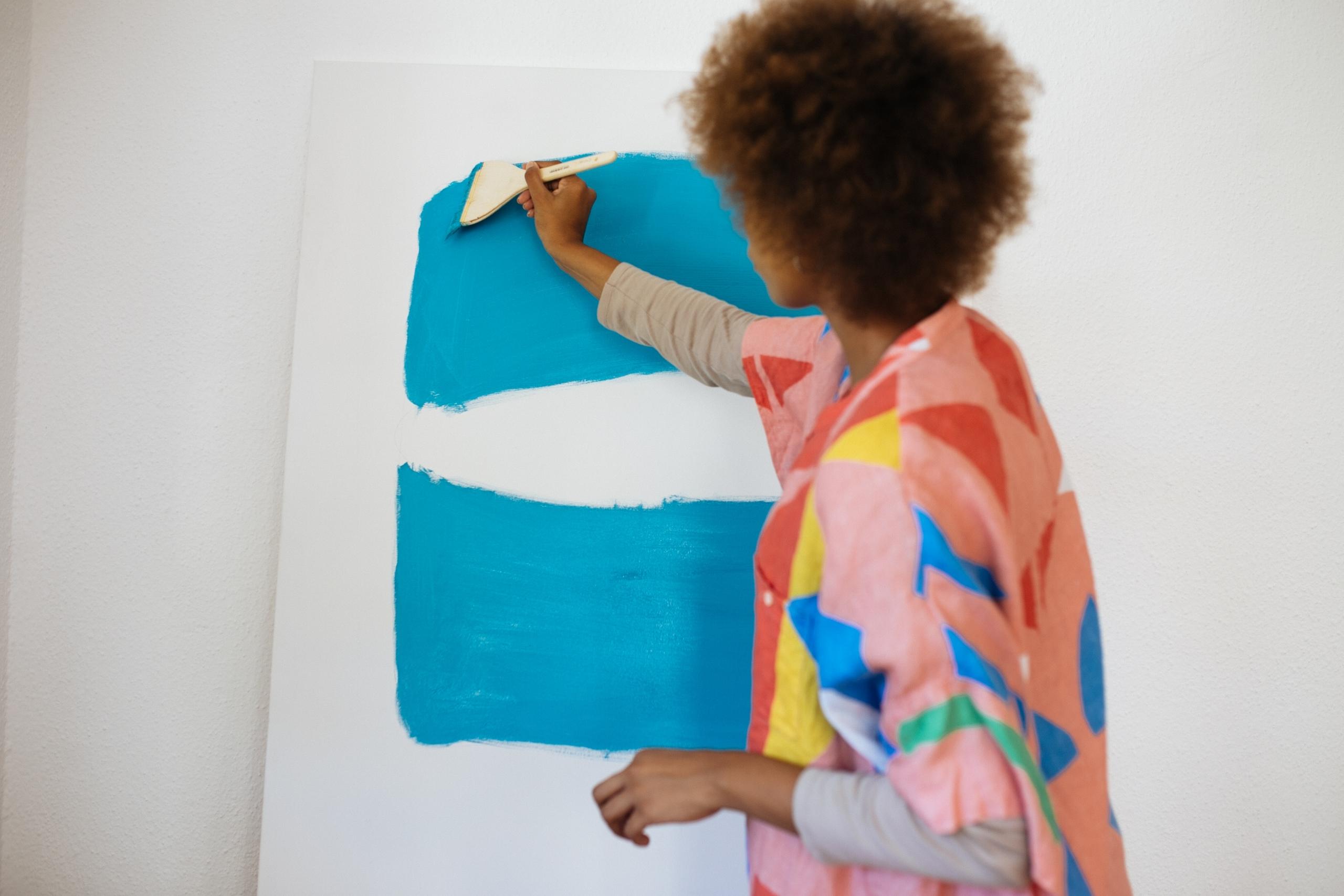 artist painting thick blue stripes on a canvas