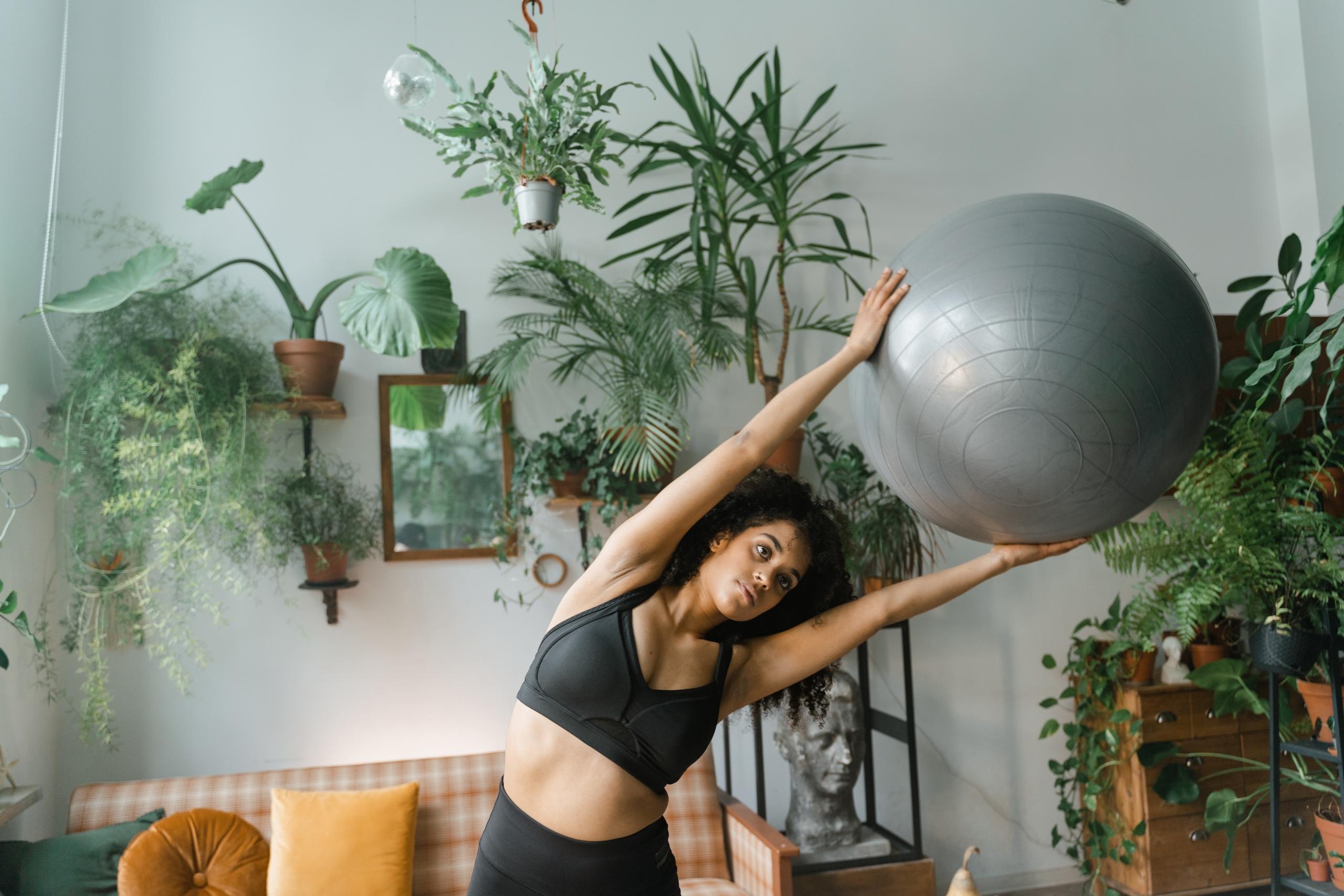person in sports clothes using exercise ball to do upper body stretches