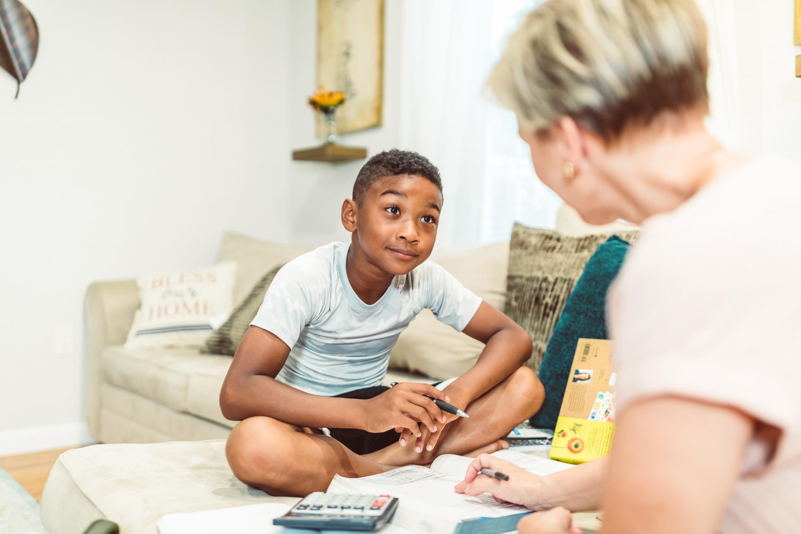 child sitting cross legged on couch listening to home teacher