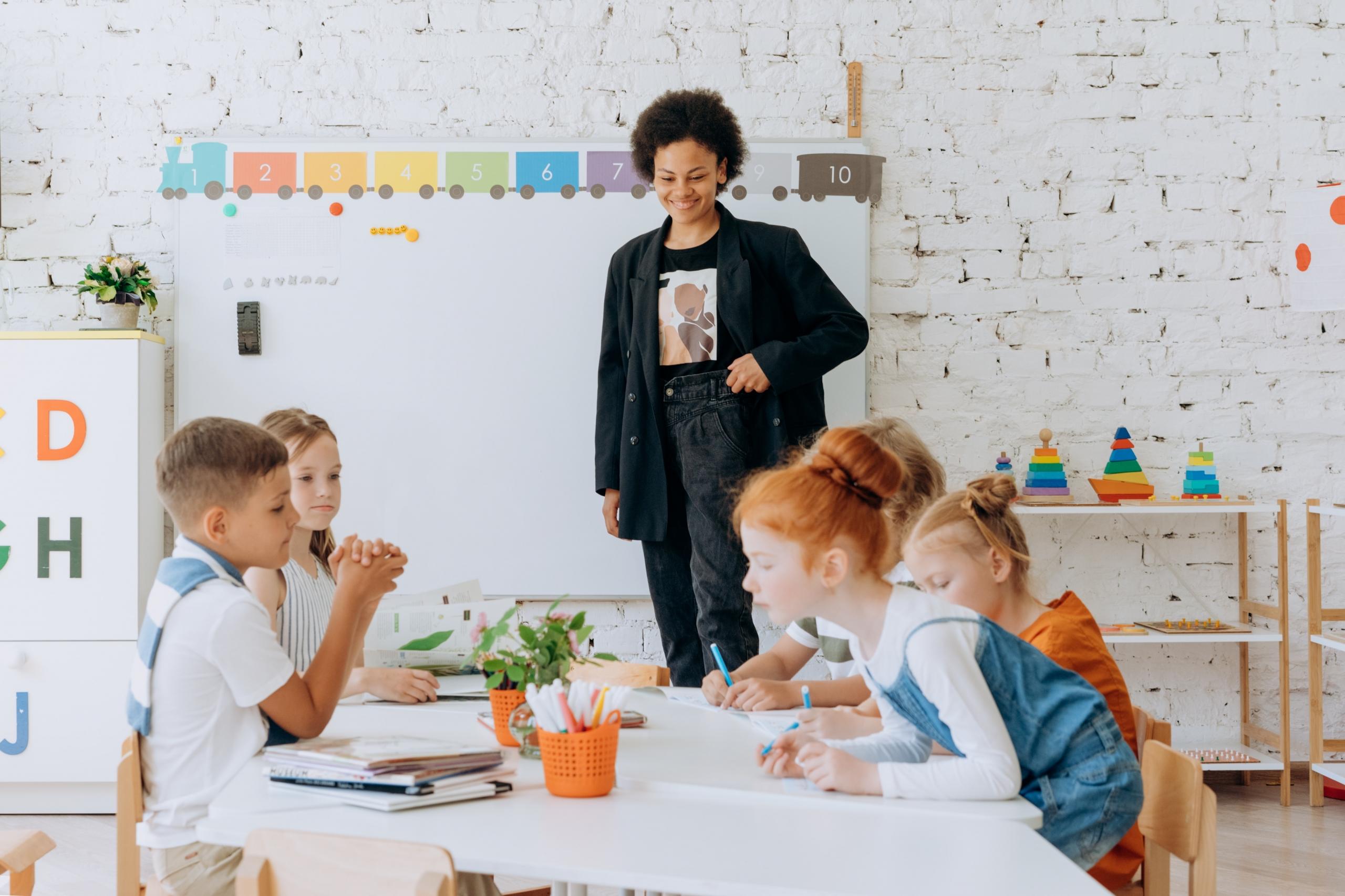 young children in classroom with teacher watching over them