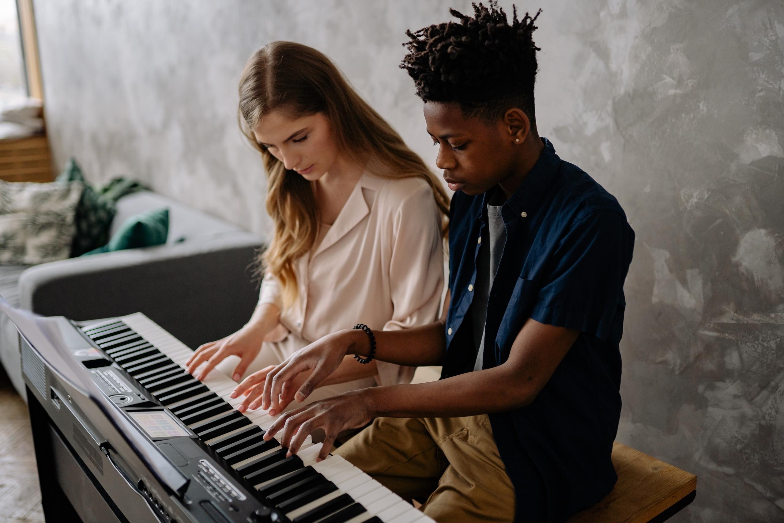 music teacher helping teen learn to play the keyboard