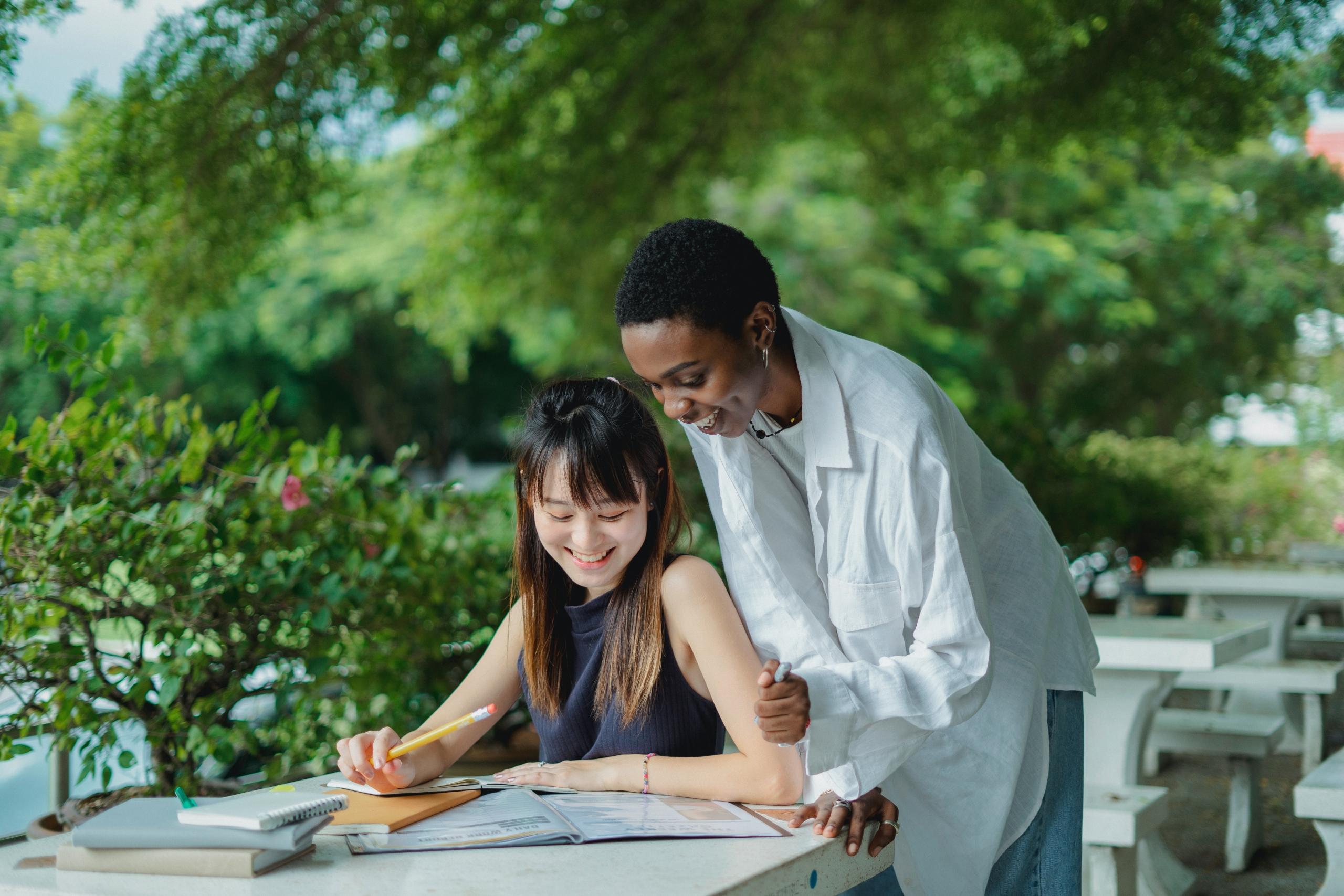 student and tutor laughing outside while reading notes