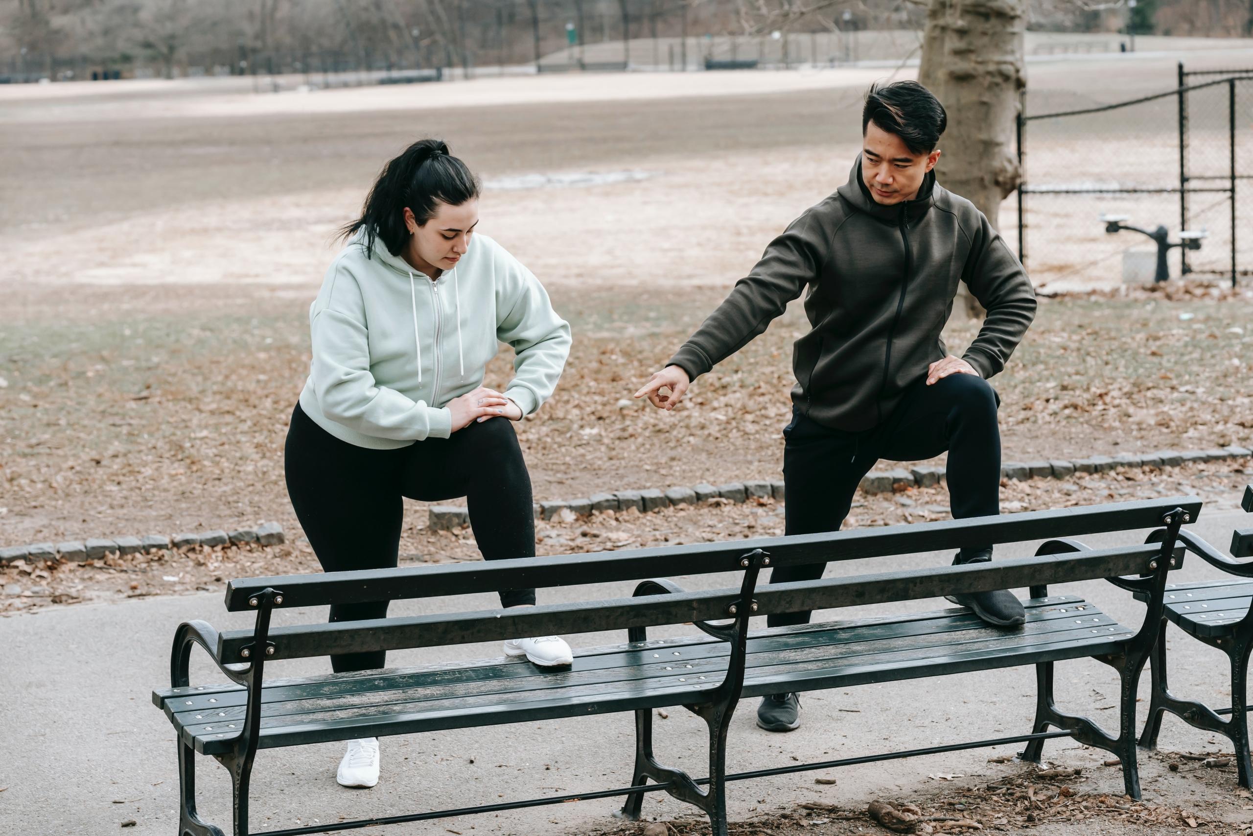 personal trainer and student working out using benches in a park