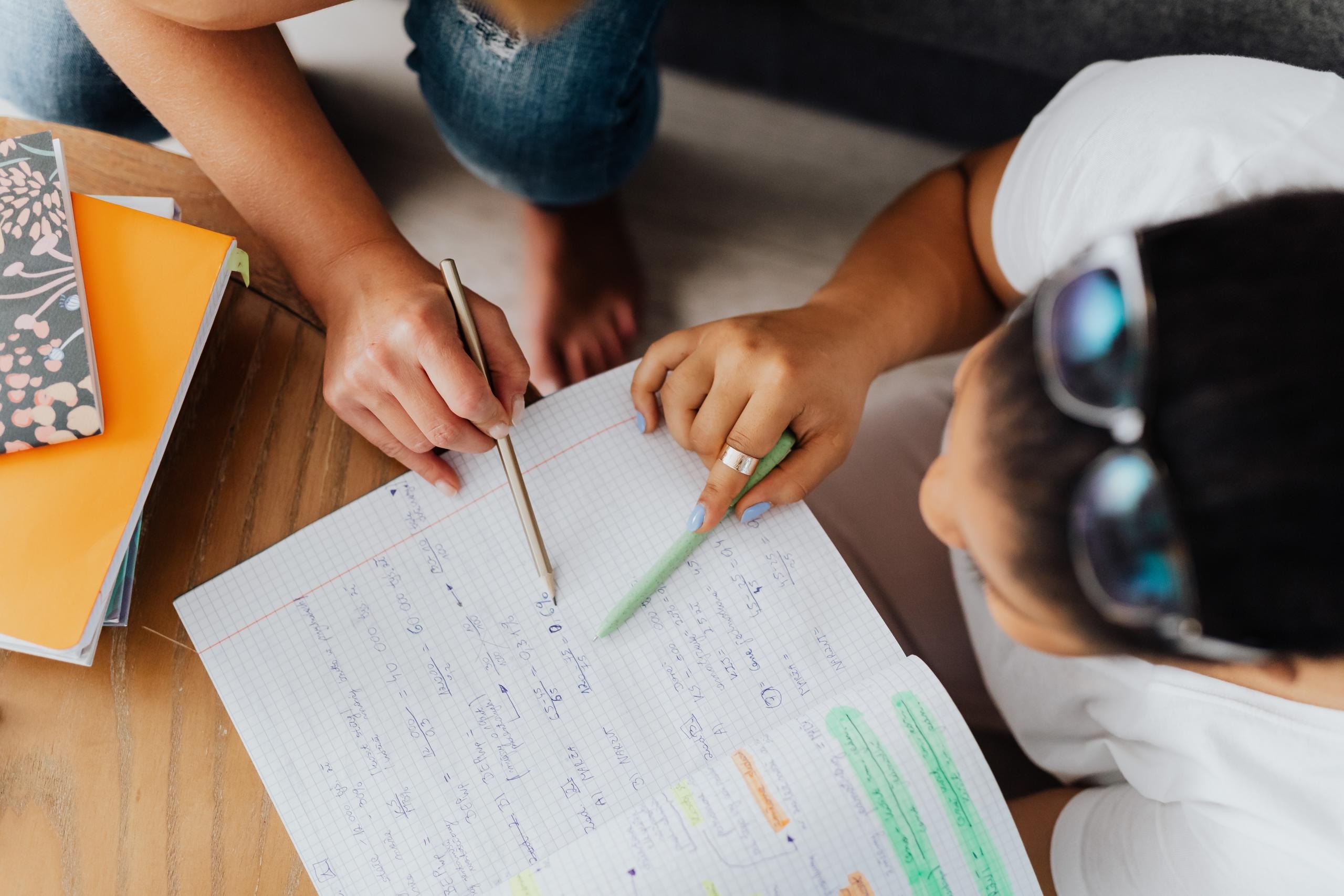 student and tutor working through Maths problems in an exercise book