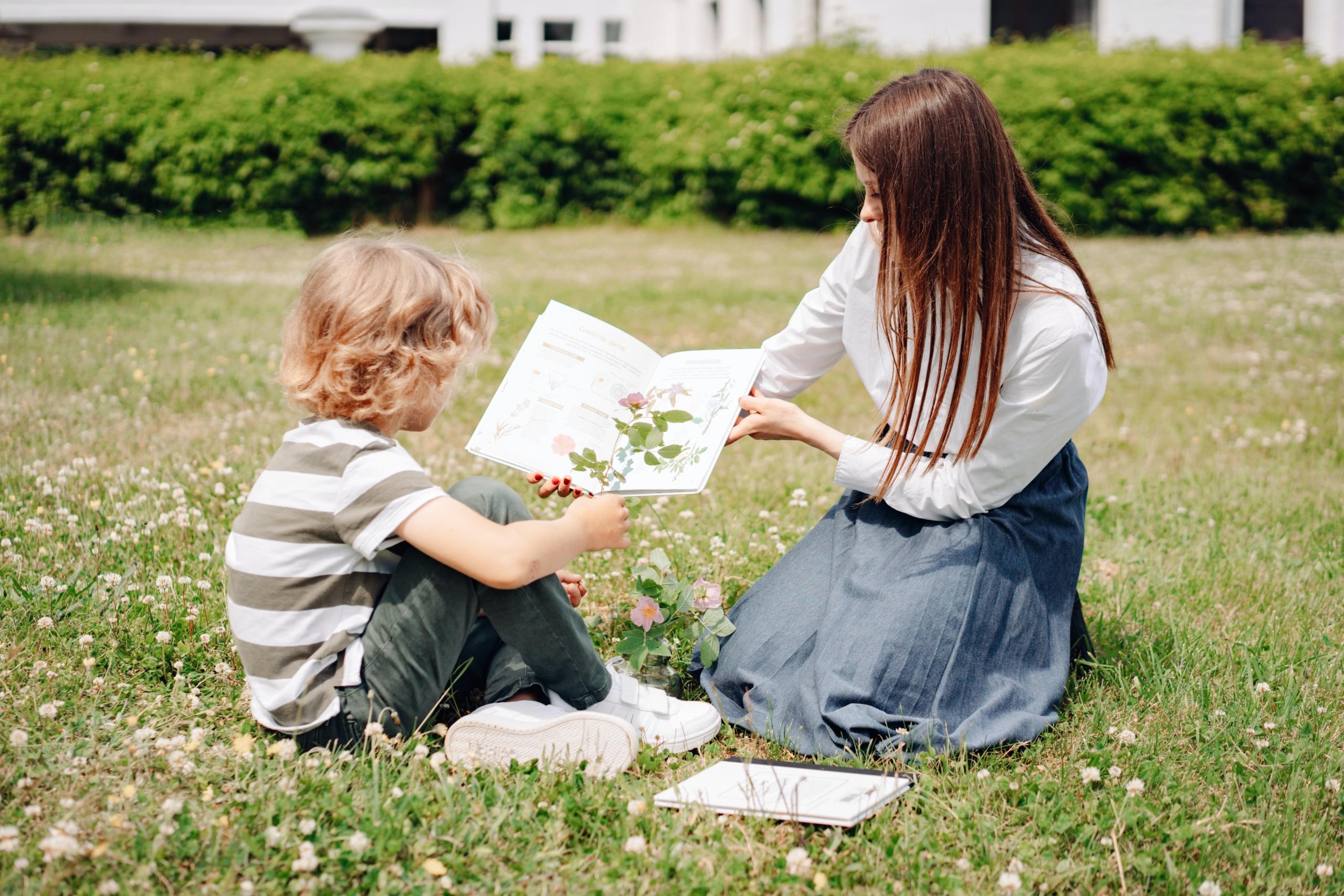 teacher using book to help young boy identify plants and flowers