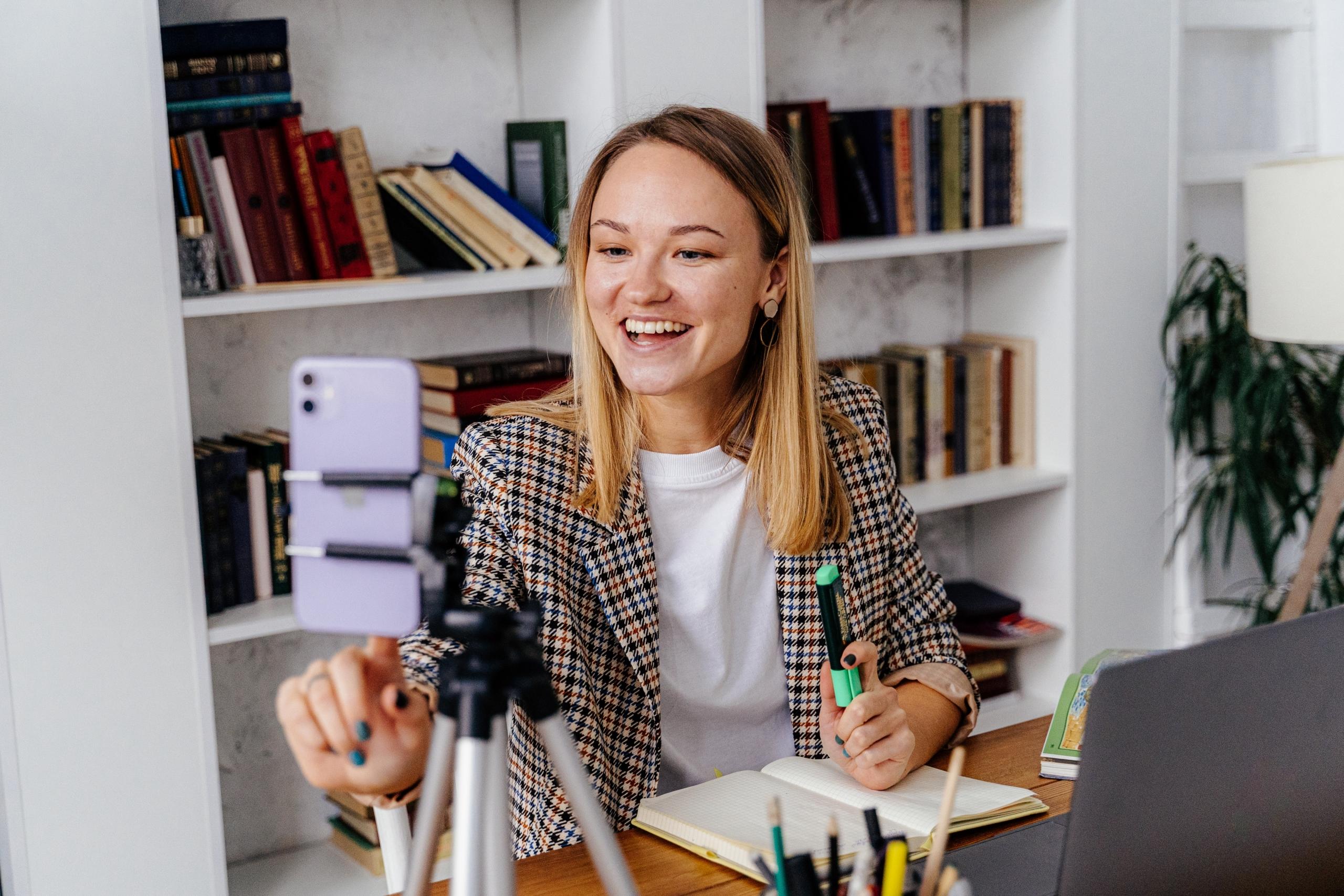 woman recording herself with smartphone whilst taking notes