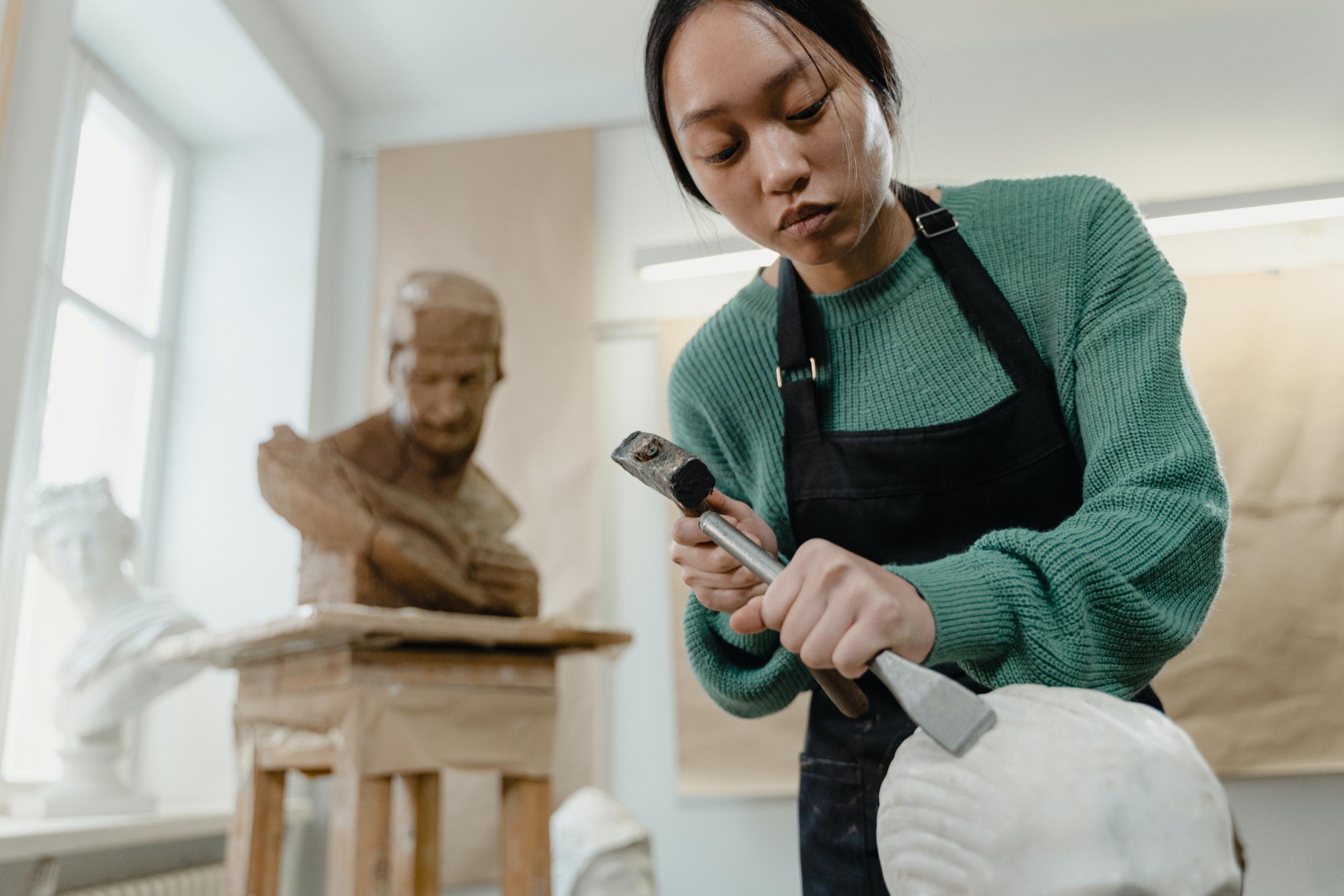 artist creating bust with chisel and hammer