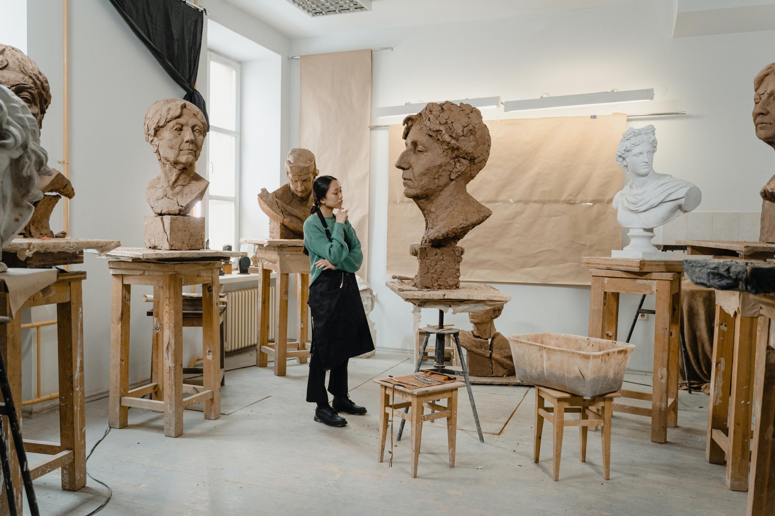 Artist examining sculptures placed on tables