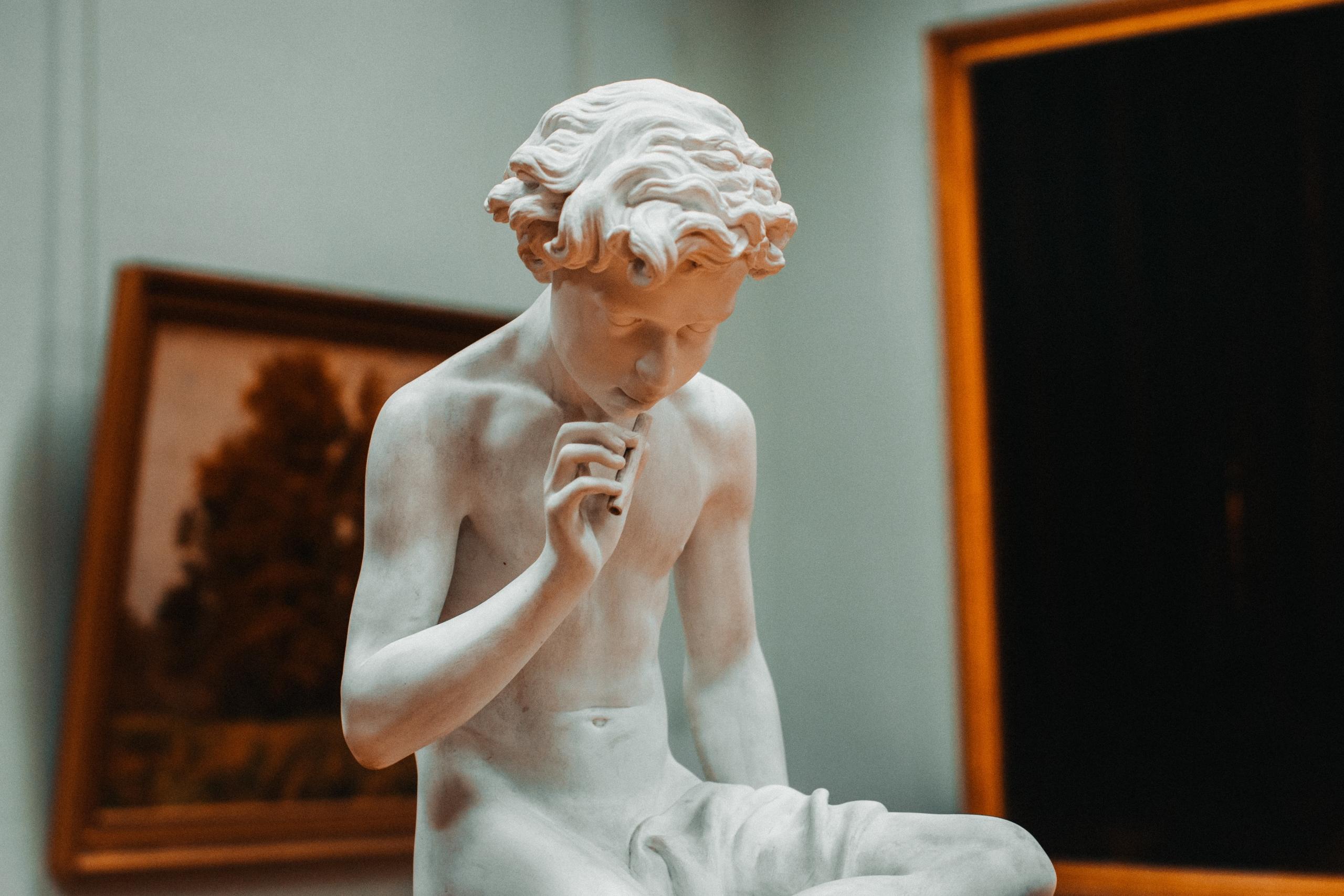 sculpture depicting a boy holding an instrument to his lips