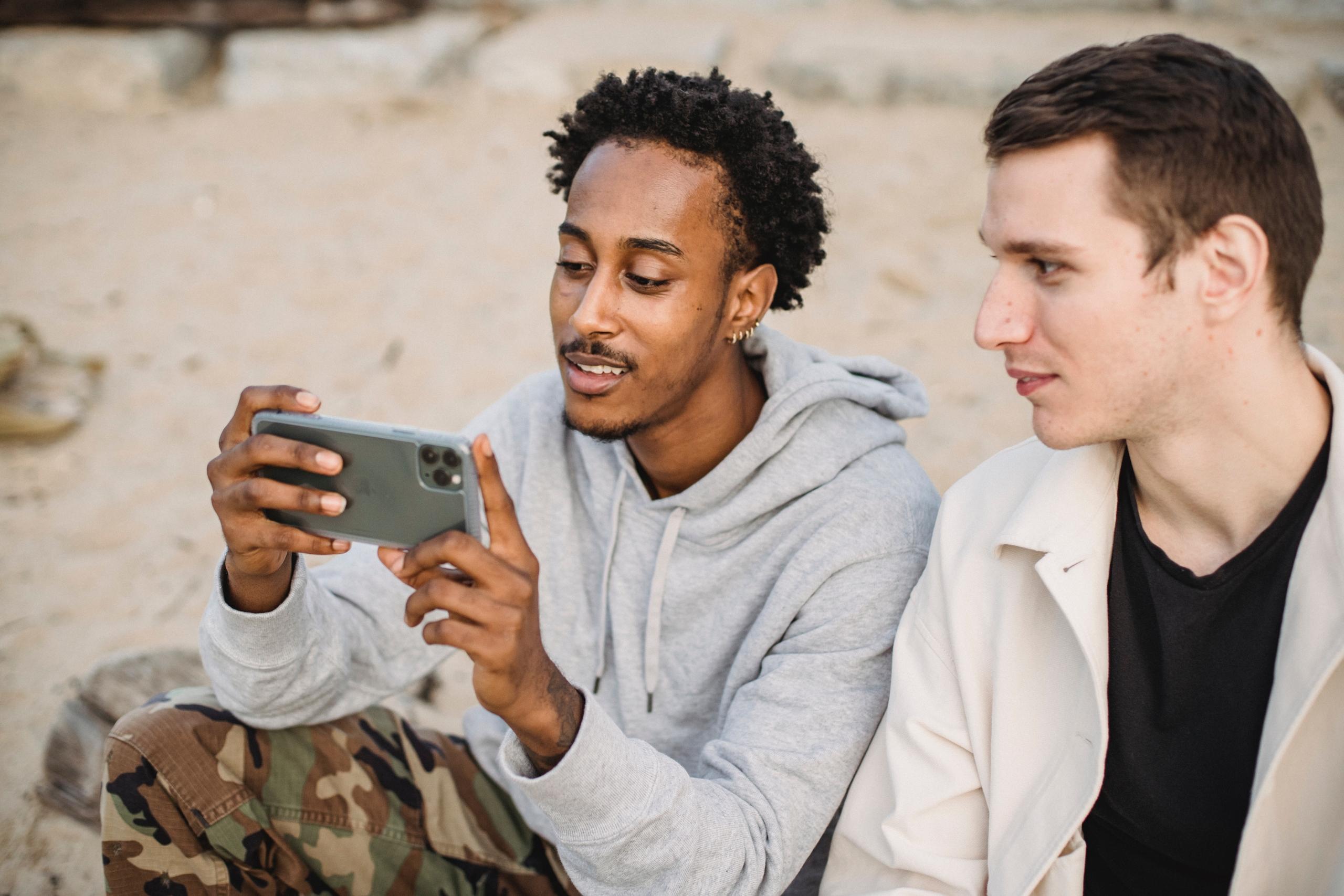 two teens looking at smartphone on the beach