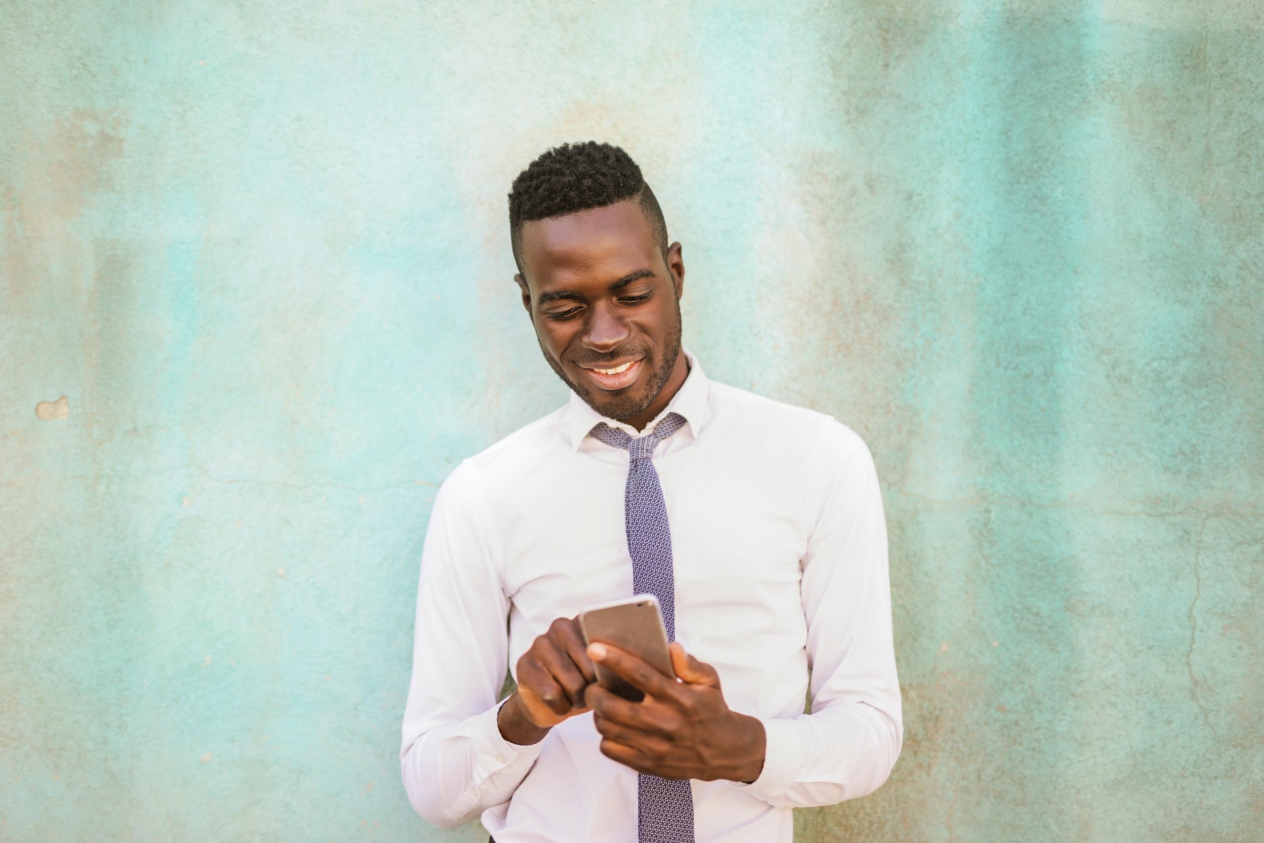 man standing infant of decorative wall scrolling social media on smartphone