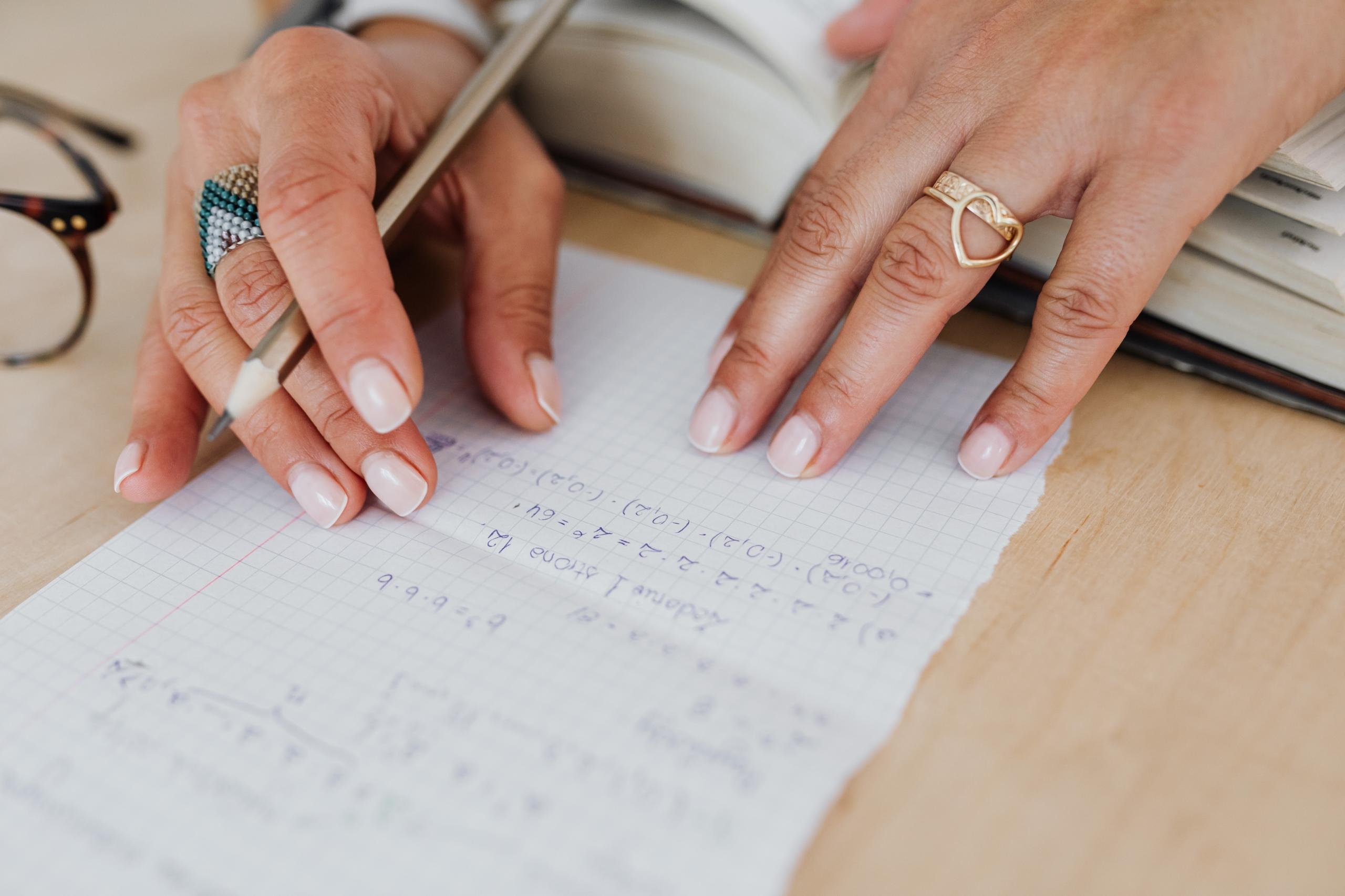person solving maths equations using pen and paper