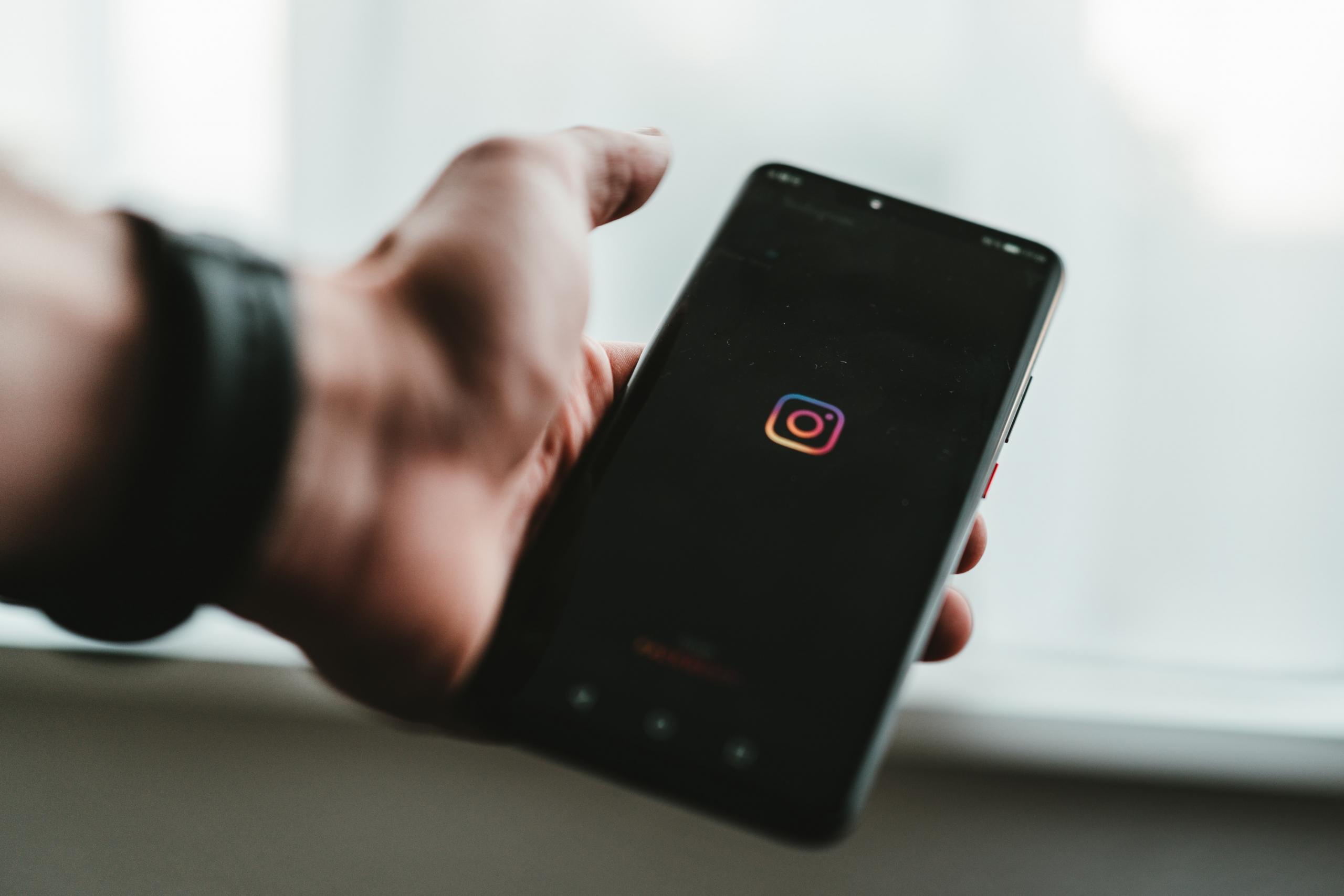person opening Instagram app on phone with black background