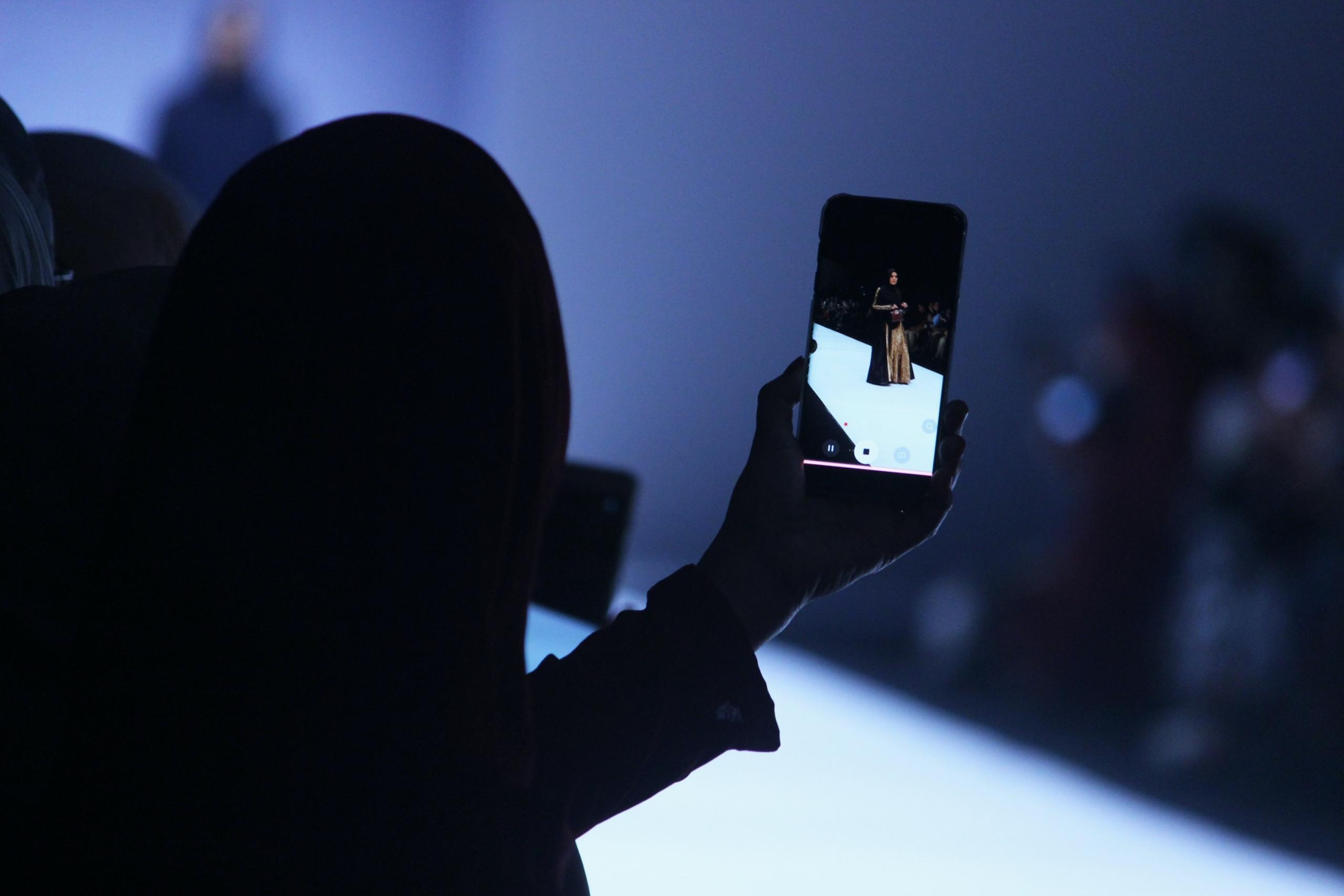 person recording catwalk show on smartphone